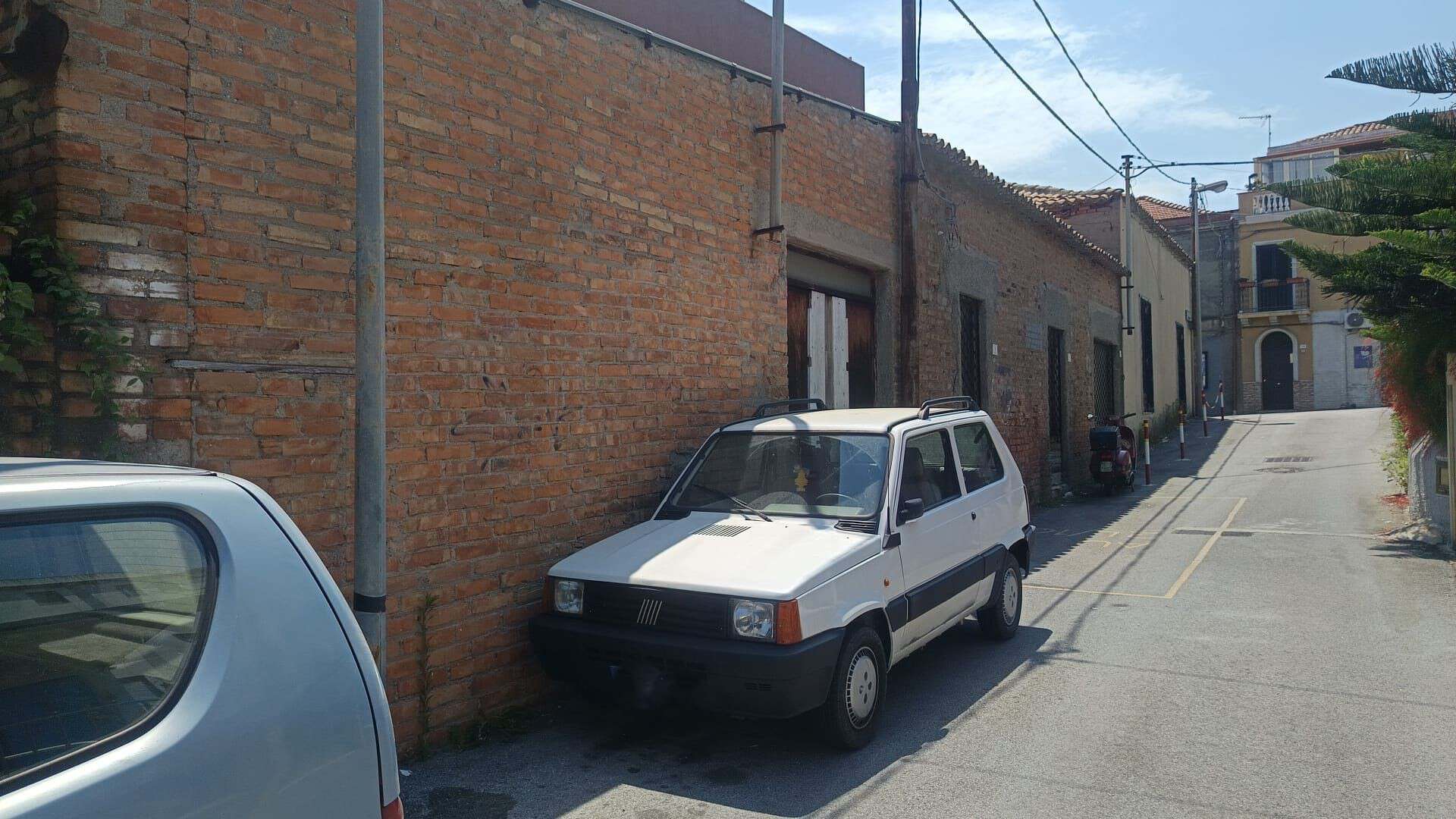 Vicolo di Villafranca Tirrena con auto parcheggiate e edifici in mattoni.