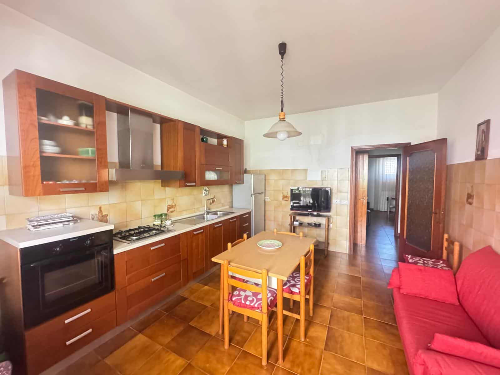 Cucina abitabile con mobili in legno, forno, frigorifero e tavolo da pranzo in stile classico, ambiente accogliente e funzionale.