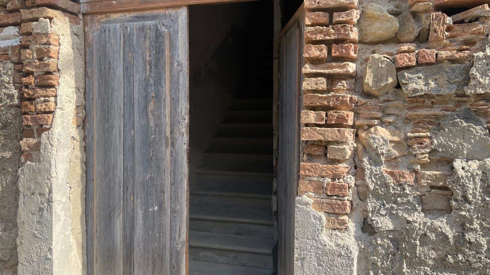 Porta in legno rustica tra muri in pietra, ingresso a una casa tradizionale.