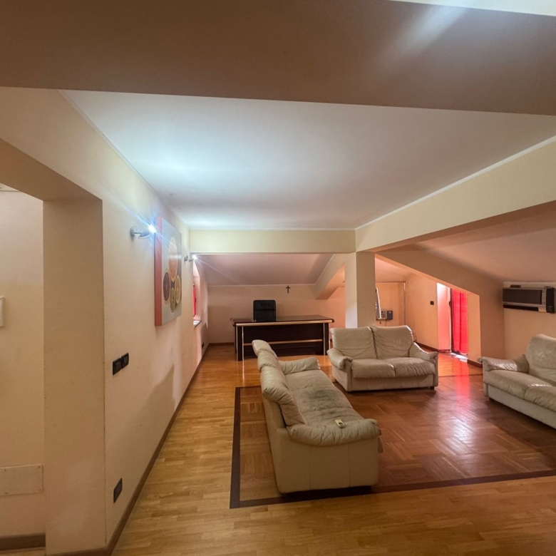 Ampio soggiorno con divani bianchi e pavimento in parquet, ambiente luminoso e accogliente.