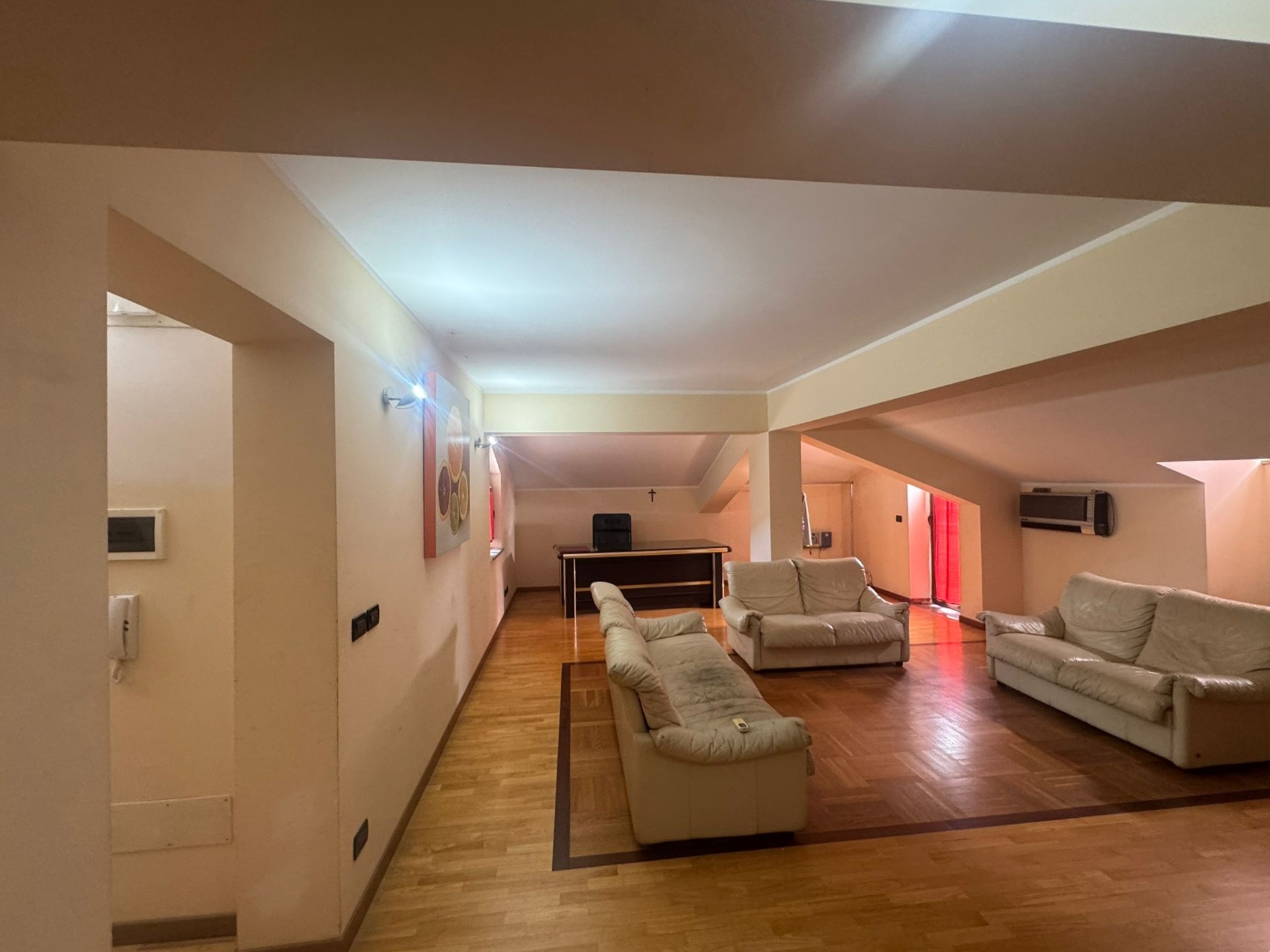 Ampio soggiorno con divani bianchi e pavimento in parquet, ambiente luminoso e accogliente.