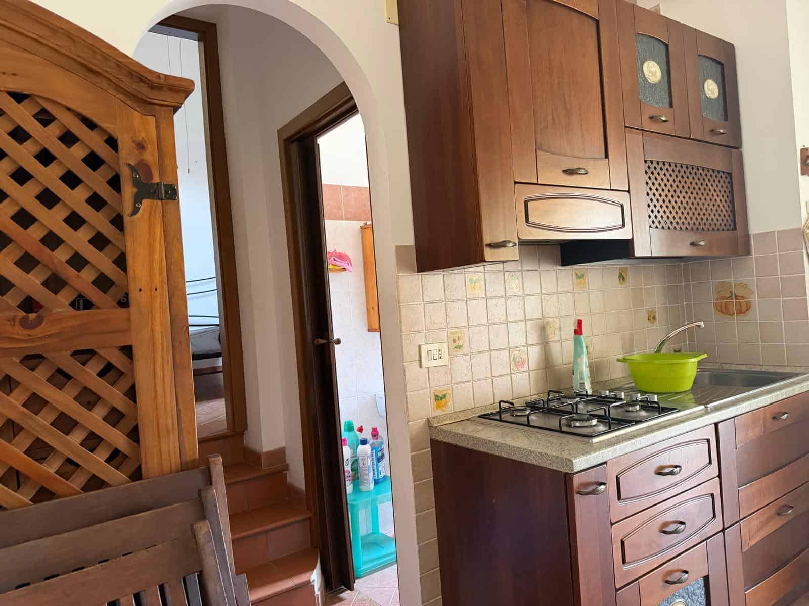 Elegante cucina in stile classico con mobili in legno scuro, piano cottura a gas e dettagli decorativi in ceramica, ideale per ambienti domestici accoglienti e funzionali.