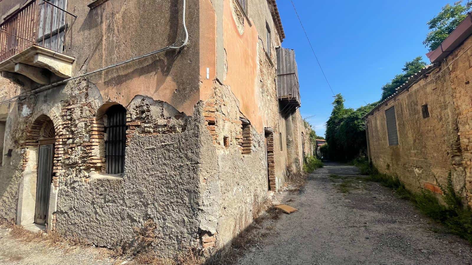 Vicolo rurale con case antiche in pietra, strada sterrata e ambiente tranquillo, ideale per chi cerca immobili storici e autentici in campagna.