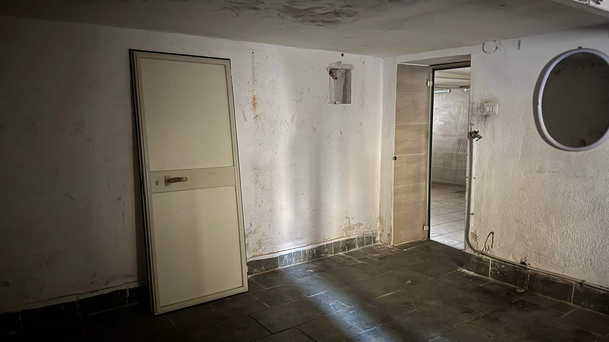 Porta da interno in stile semplice, pareti con segni di umidità e muffa.