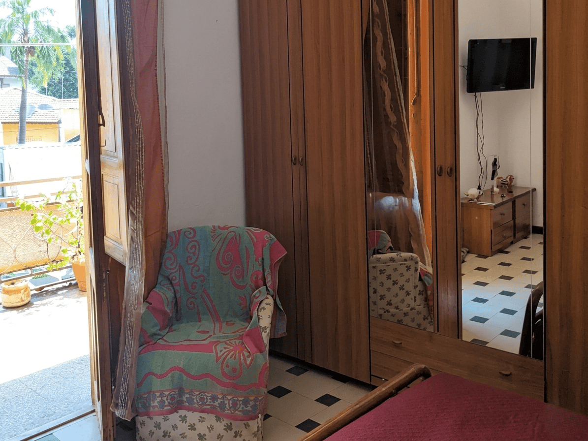 Elegante armadio in legno con specchio e soggiorno con TV, in un ambiente domestico accogliente e luminoso, ideale per la vendita o l'affitto di immobili residenziali.