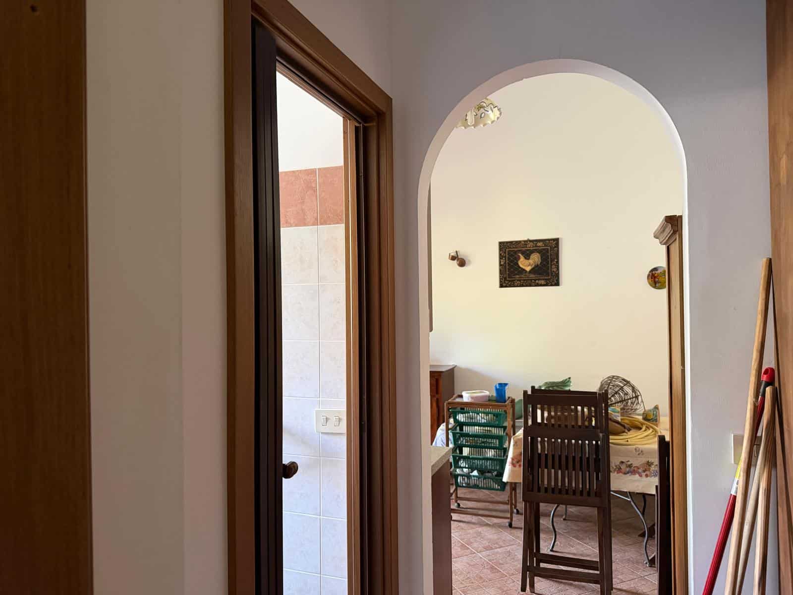 Ampia porta a vetri che conduce a una zona pranzo luminosa e accogliente, con arredi in legno e decorazioni eleganti, ideale per vivere momenti conviviali in casa.