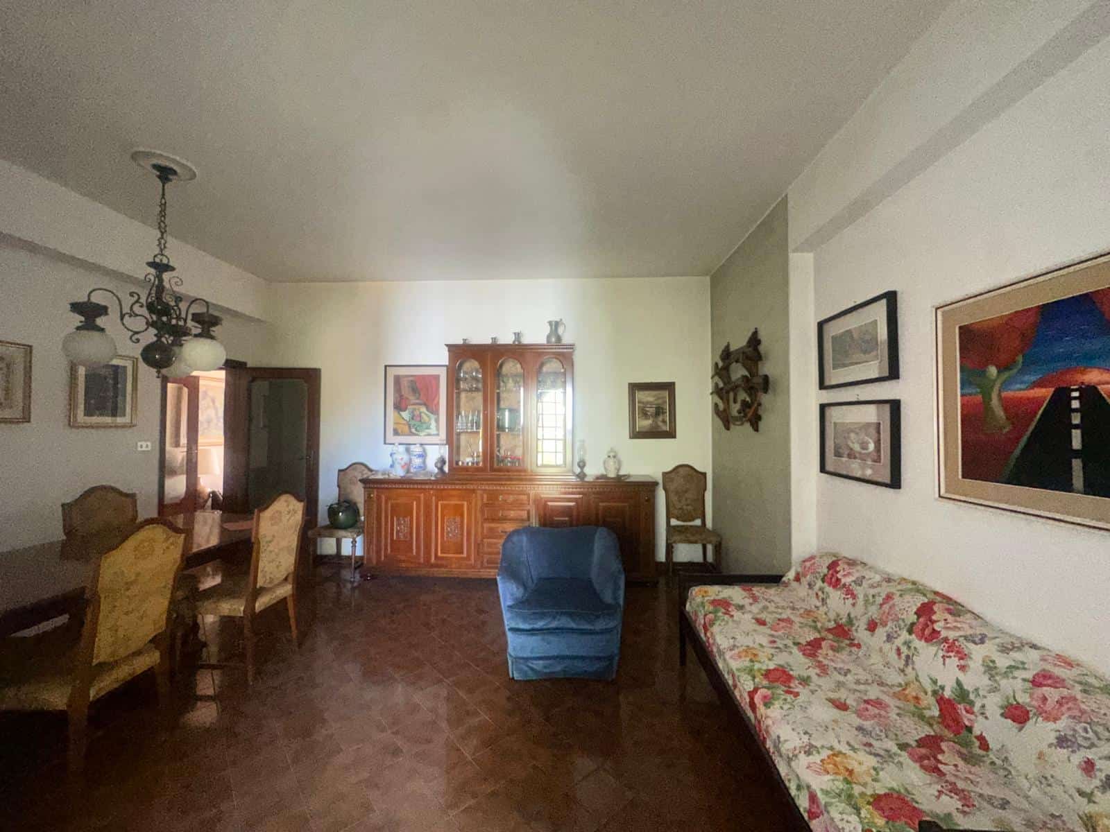 Ampio soggiorno con mobili d'epoca, divano floreale e pareti decorate, ideale per vivere momenti di relax e convivialità in un ambiente accogliente e luminoso.