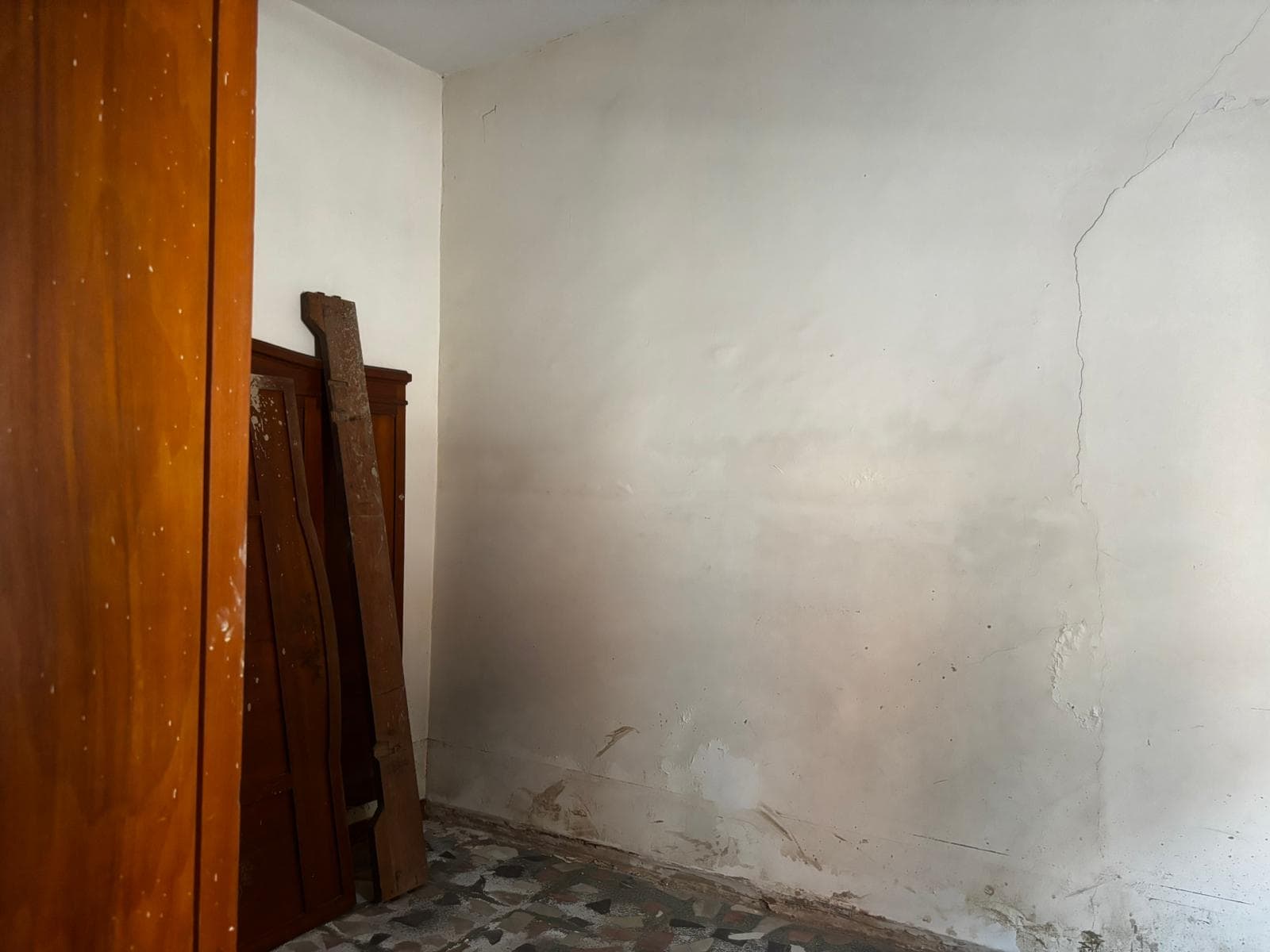 Senza titolo, immagine di una stanza vuota con pareti bianche e pavimento in piastrelle, in fase di ristrutturazione o rinnovamento.