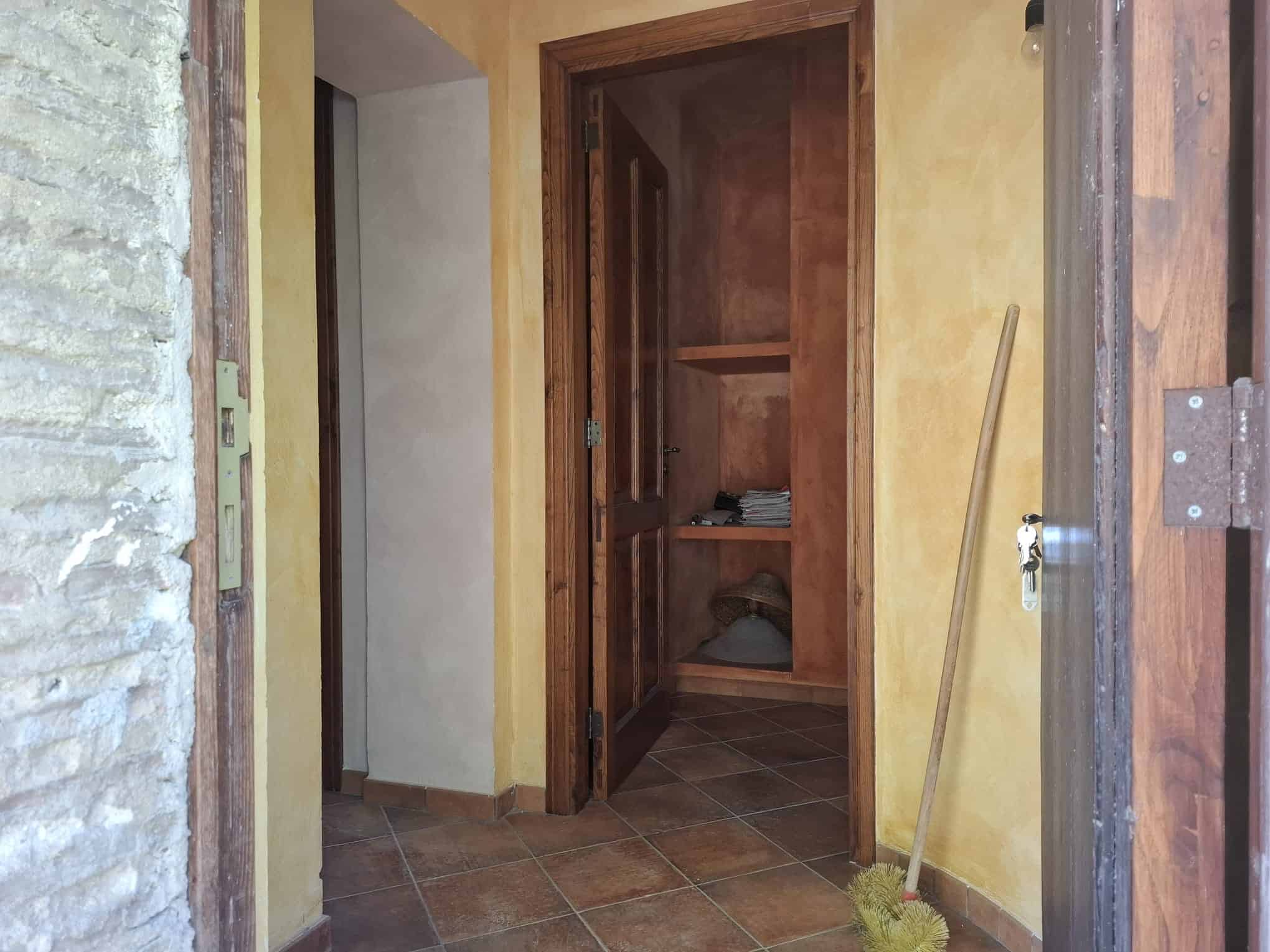 Armadio in legno con ripiani e porta aperta in un ambiente domestico rustico, dettagliato e funzionale.