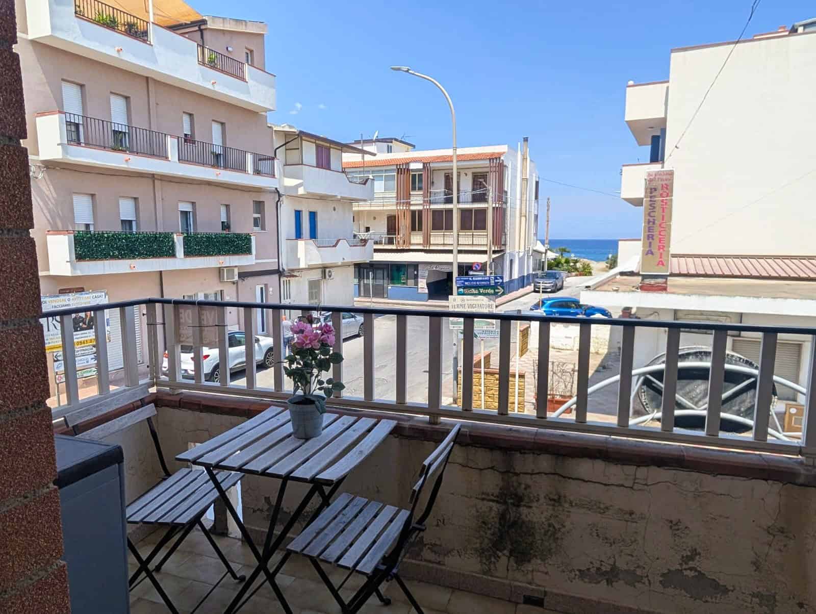 Balcone con vista mare e arredamento semplice, ideale per relax e colazioni all'aperto, in zona residenziale vicino al mare.