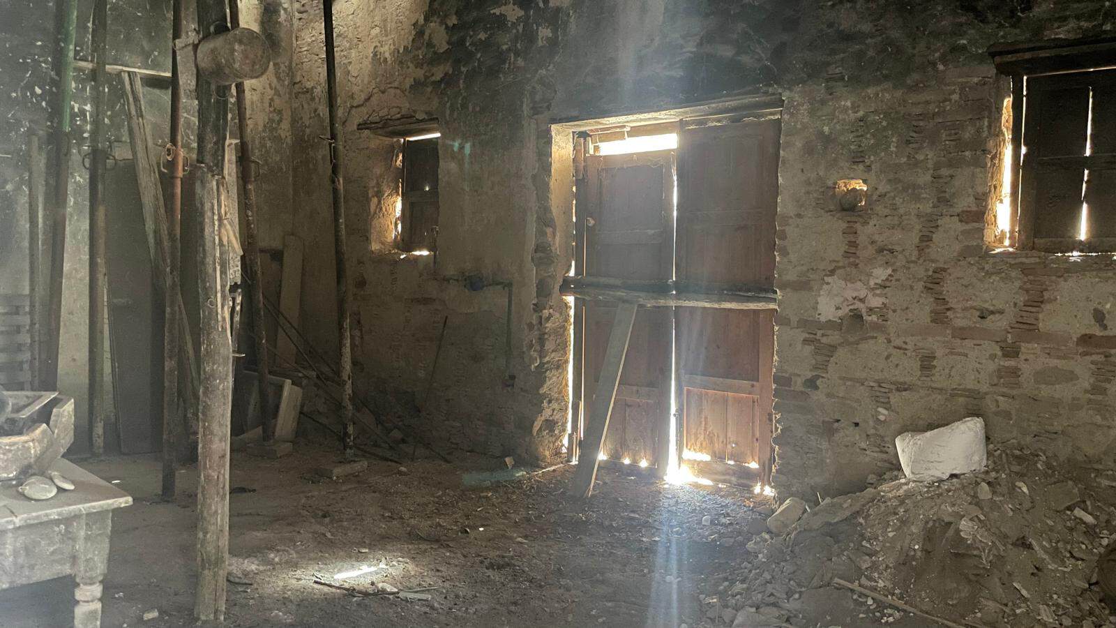 Ristrutturazione di un edificio abbandonato con pareti in pietra e finestre danneggiate, pronto per un restauro.