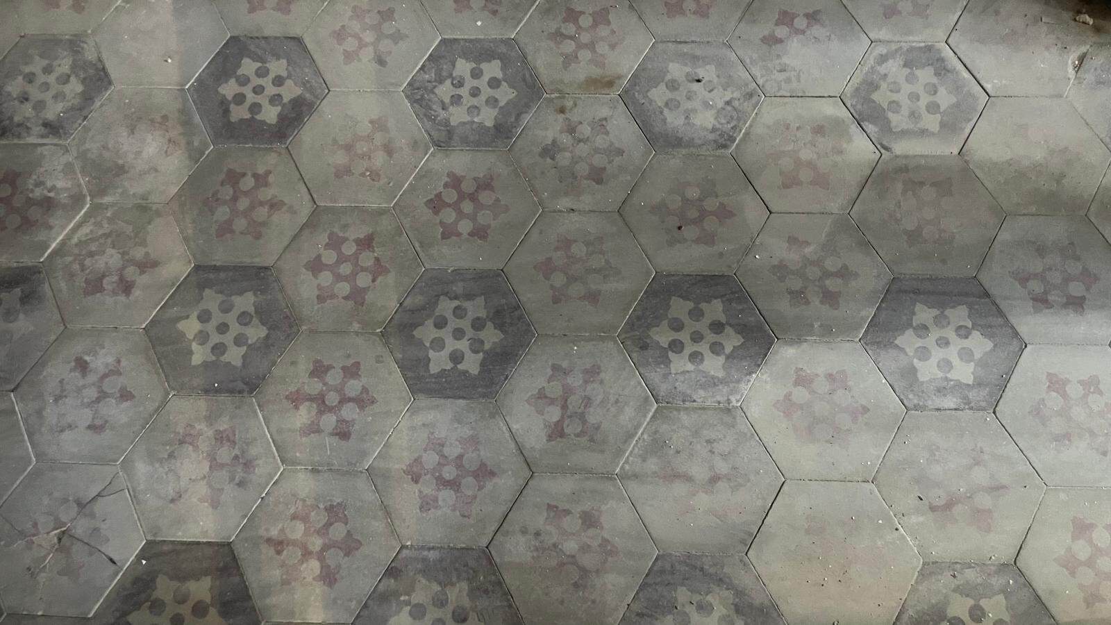 Piastrelle esagonali vintage per pavimenti interni ed esterni, con motivo decorativo in tonalità neutre e rosse, ideale per ambienti eleganti e di design.