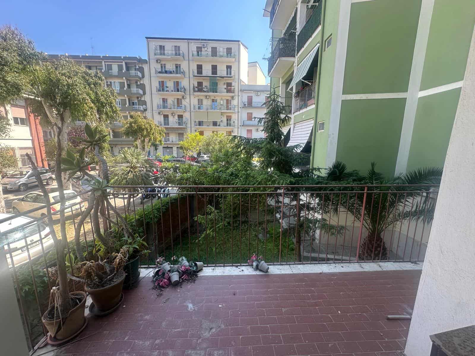 Ampia terrazza con piante e fiori, vista su edifici residenziali in un quartiere urbano, ideale per relax e socializzazione, in un appartamento in vendita o in affitto a NextCasa.