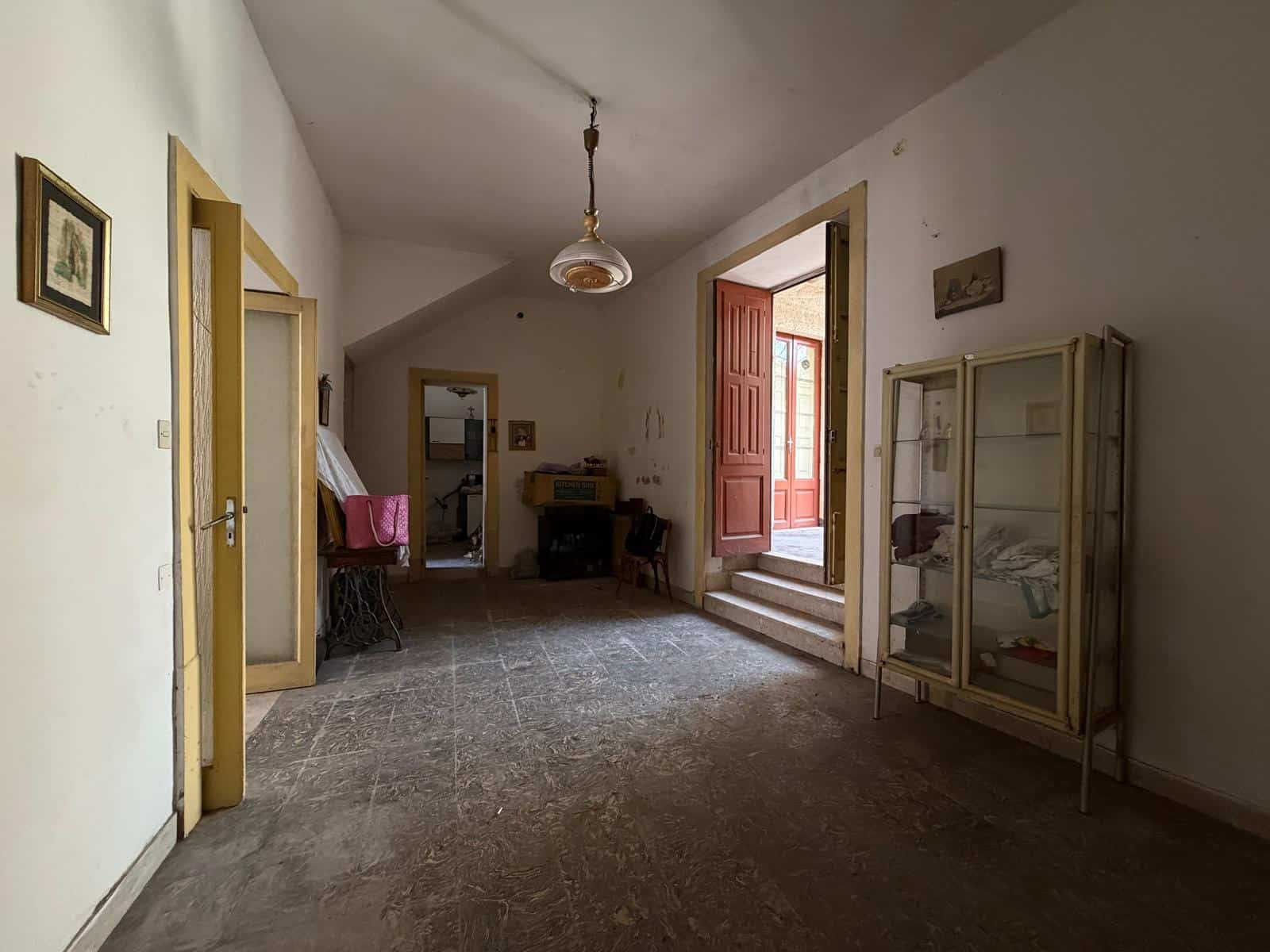 Spazioso interno di una casa indipendente in vendita a Barcellona P.G., con ingresso, soggiorno e accesso al balcone esterno.