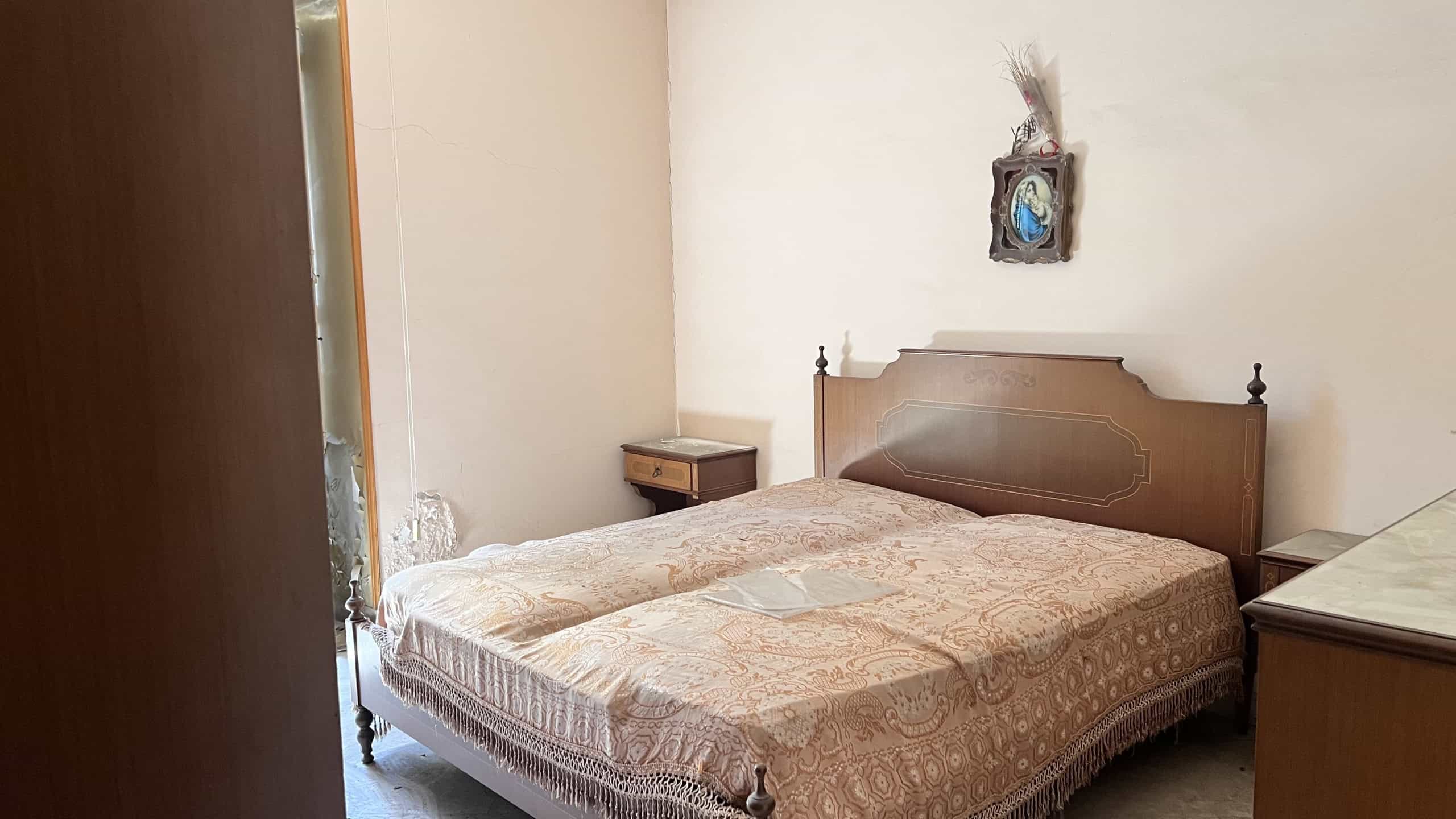 Camera che mostra una camera da letto con letto matrimoniale, comodini e decorazioni semplici.