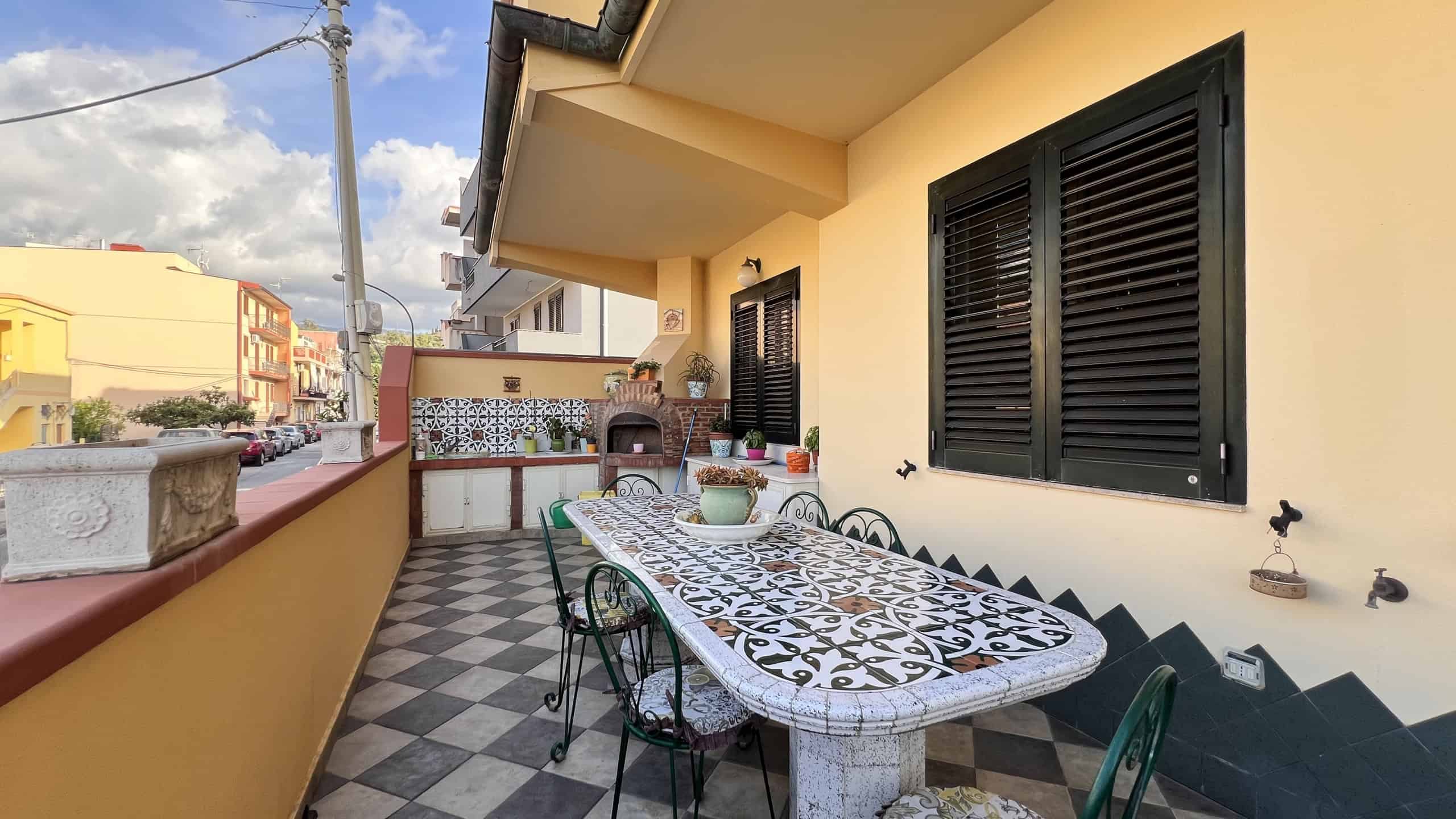 Balcone di una villa unifamiliare in vendita a Villafranca Tirrena con vista sulla strada e arredato con tavolo e sedie.