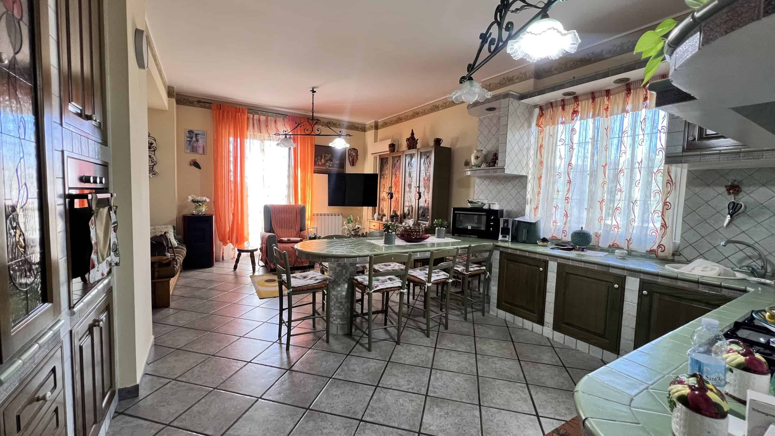 Interno di una villa unifamiliare con cucina e zona soggiorno luminosa, arredamento accogliente e dettagli tradizionali.