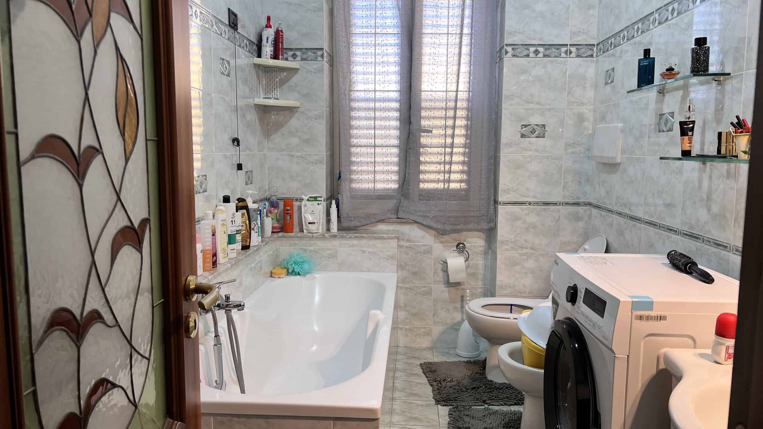 Bagno moderno con vasca, lavatrice e accessori, in una casa in vendita a Villafranca Tirrena.