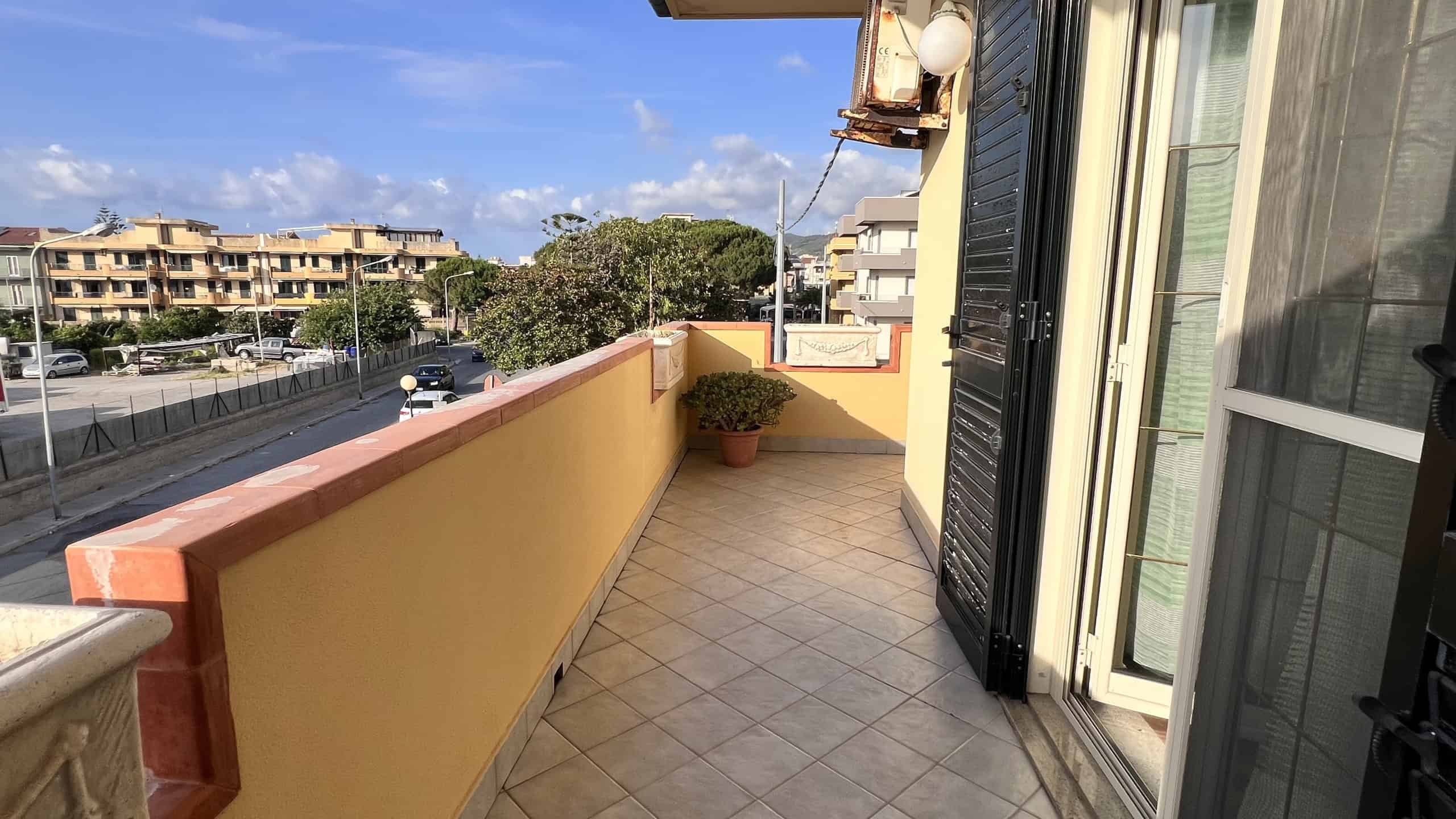 Balcone di una villa in vendita a Villafranca Tirrena con vista sulla strada e edifici circostanti.