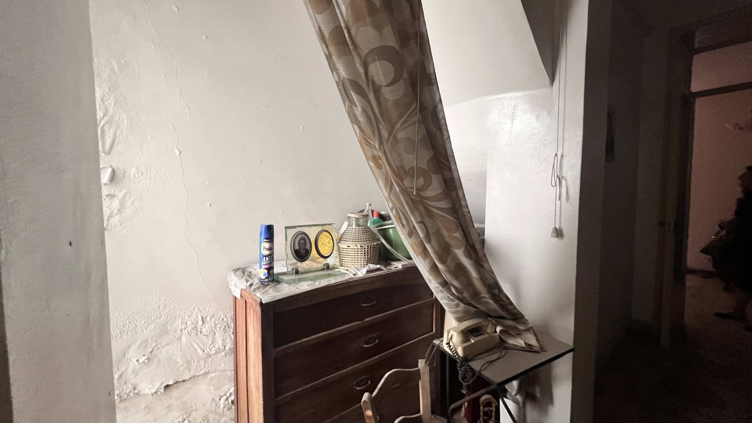 Interno di un appartamento con armadio e finestra con tende, ambiente luminoso e semplice.