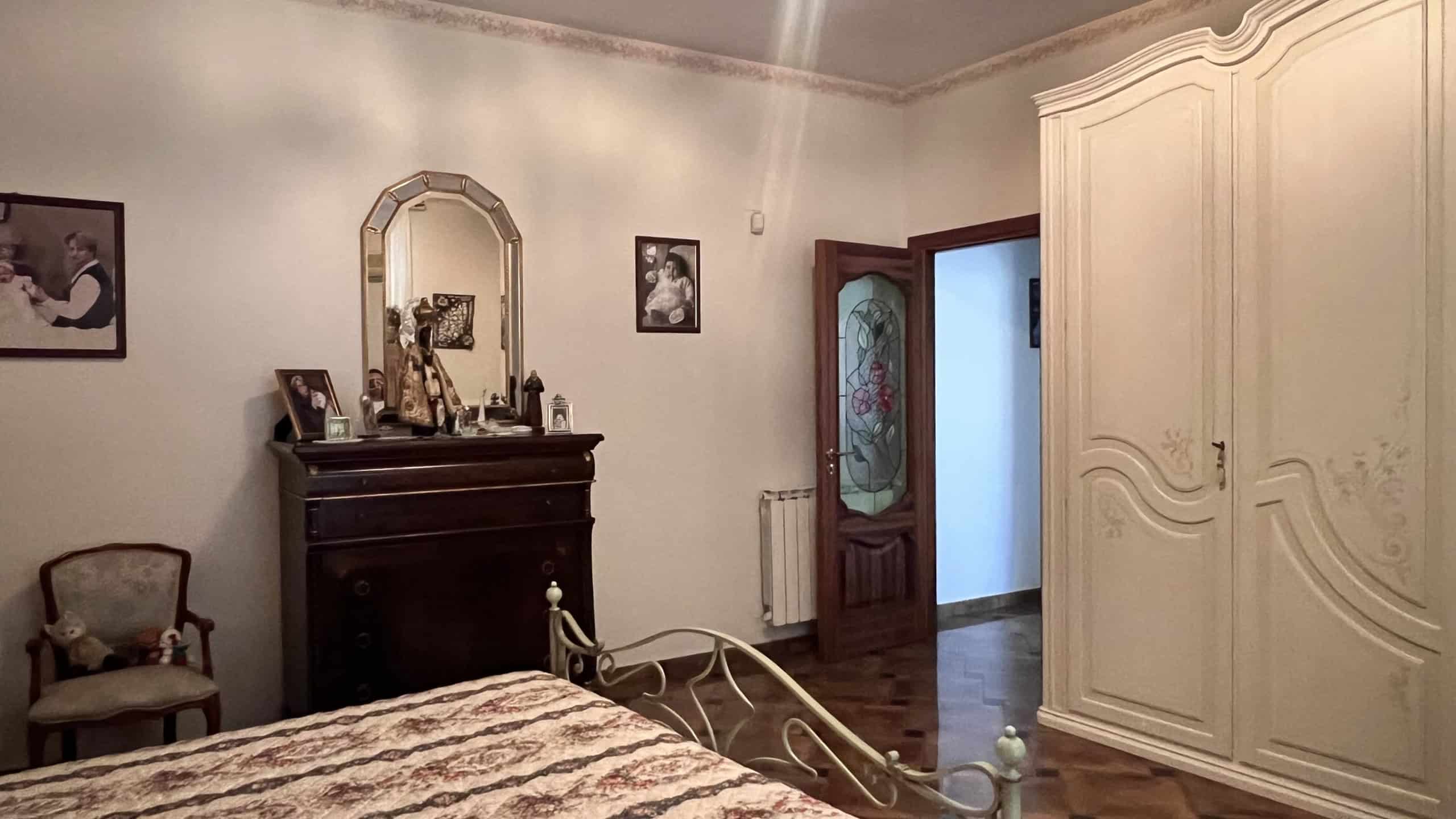 Interno di una camera da letto in stile classico con armadio grande e mobili in legno chiaro.