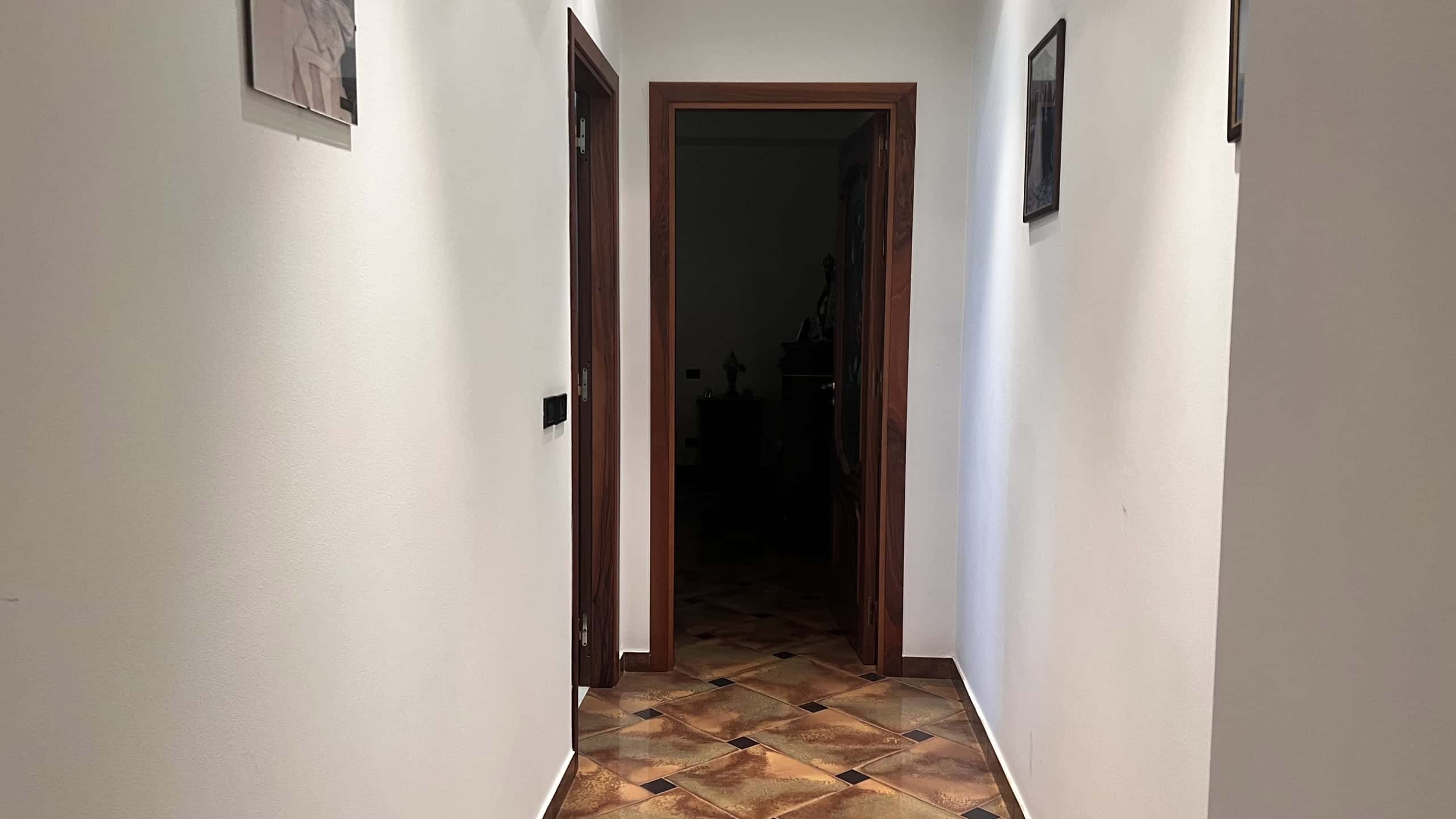 Corridor interno di una villa unifamiliare con pareti bianche e pavimento in piastrelle colorate.