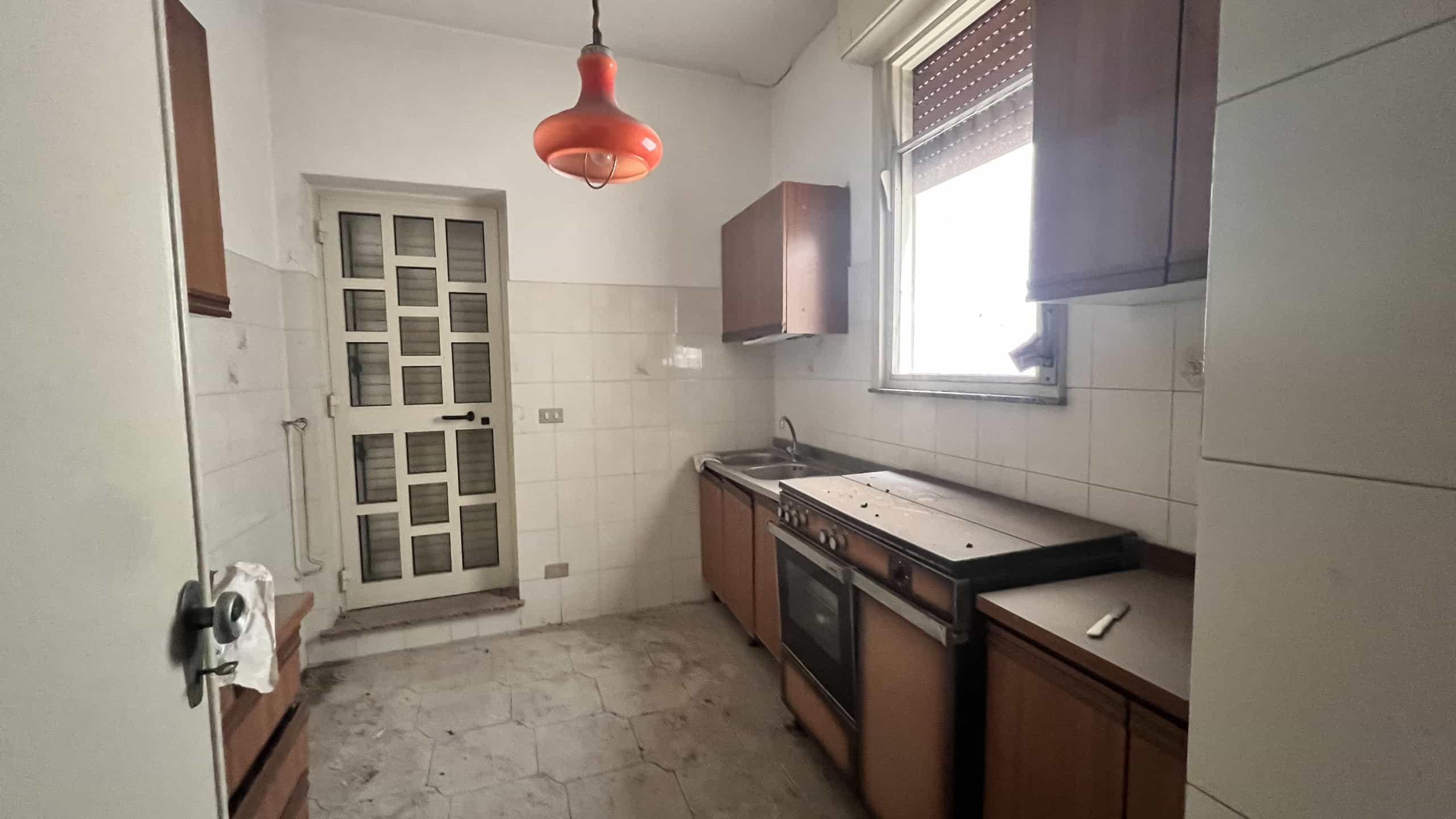 Cucina abitabile con finestra, mobili in legno e piano cottura a gas in un appartamento in vendita a Scaletta Zanclea.
