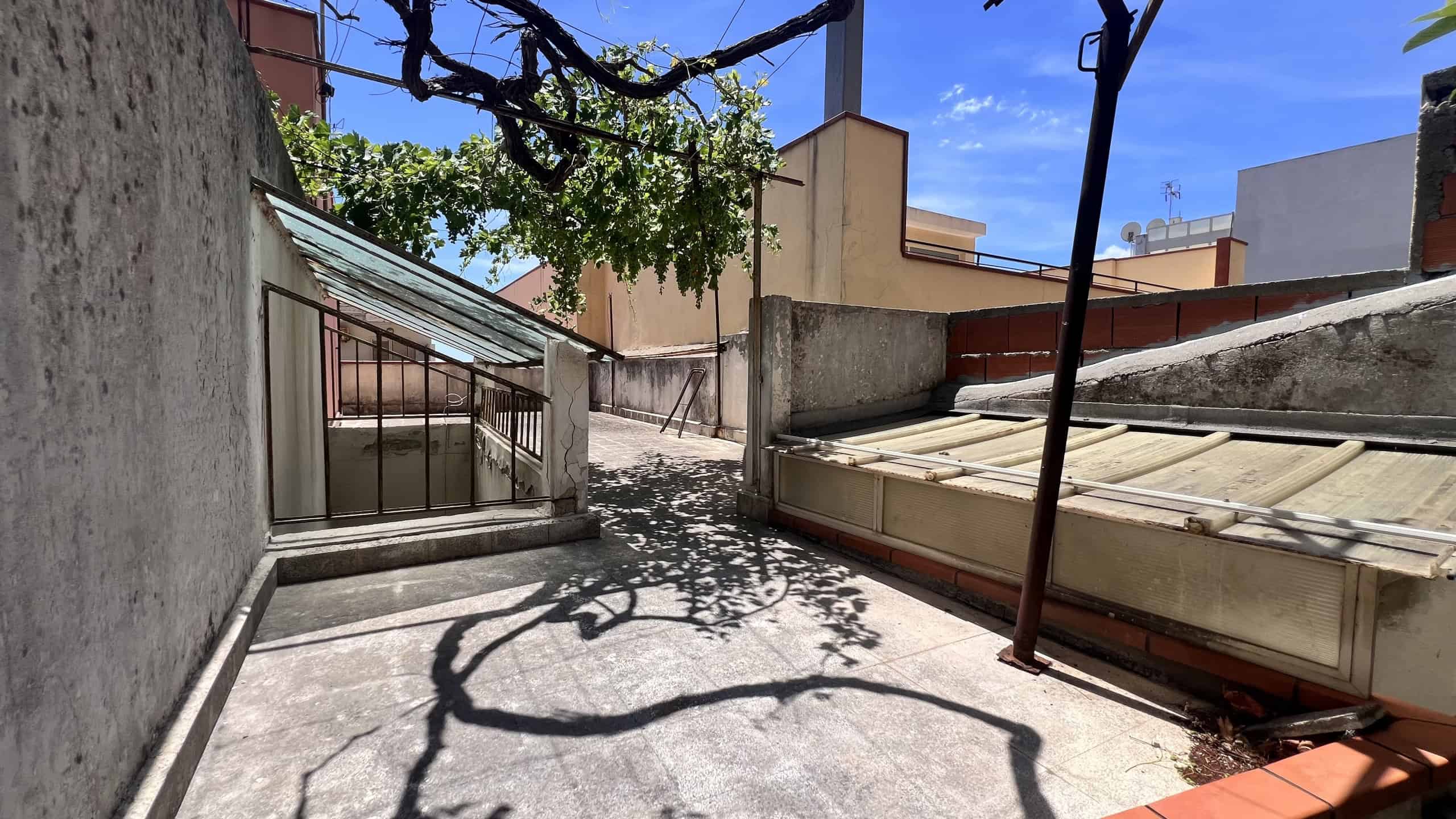 Terrazza con ombra di albero e vista urbana, ideale per relax e socializzare.