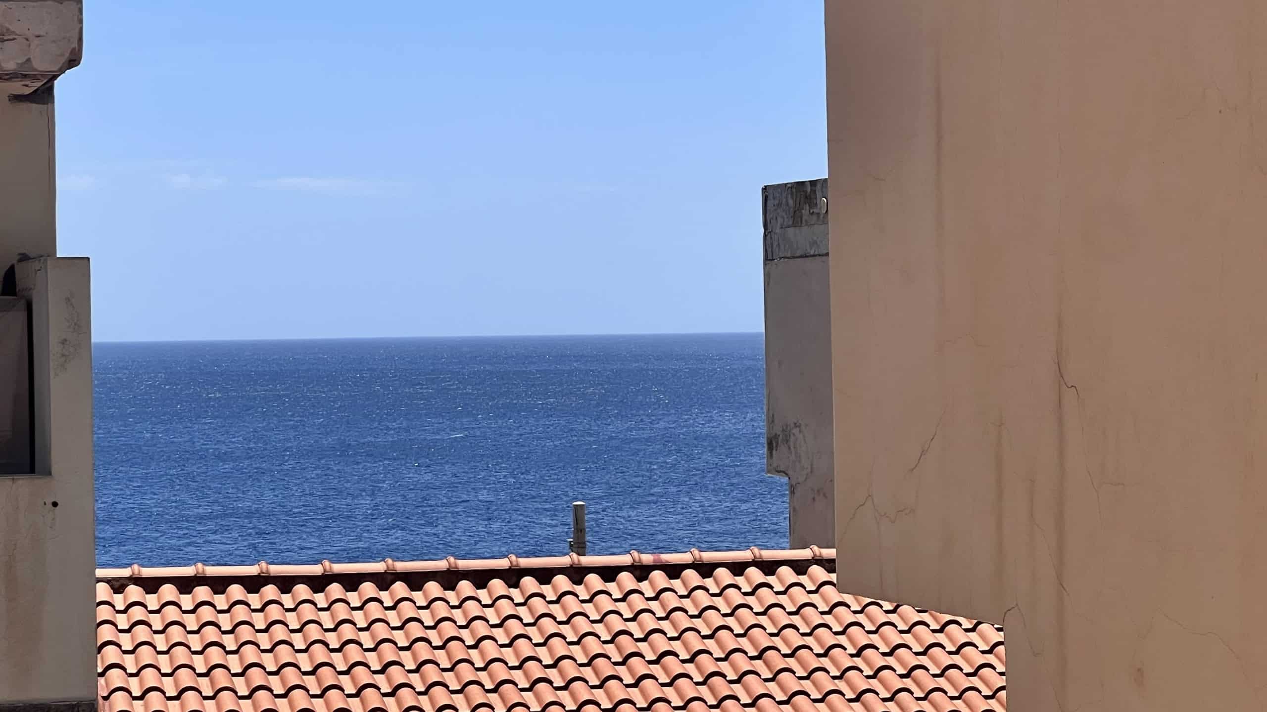 Vista mare dall'appartamento in Via Roma 168, Scaletta Zanclea, con tetto in terracotta e pareti beige.