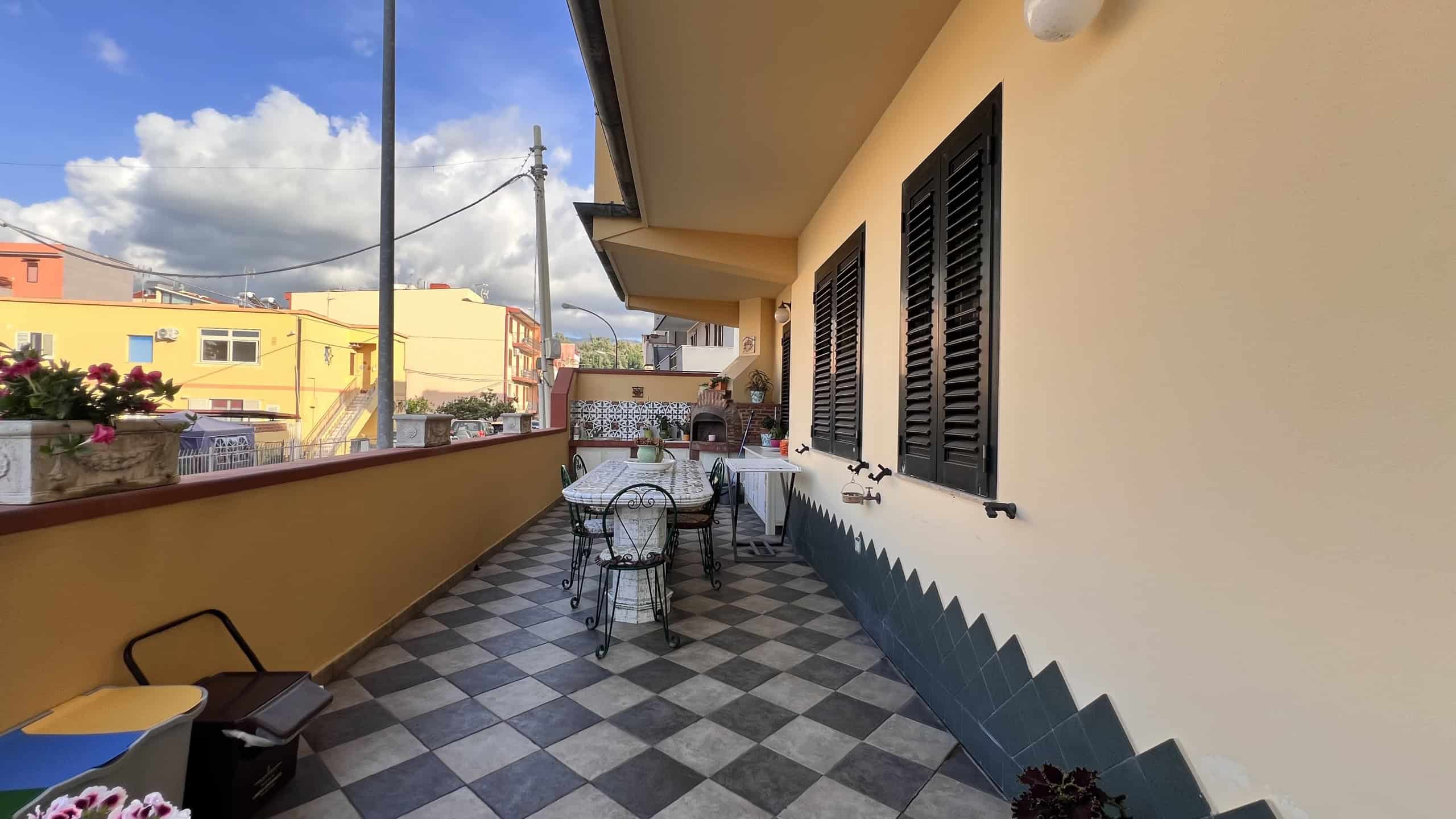 Balcone di una villa in vendita a Villafranca Tirrena con vista su edifici colorati e cielo nuvoloso.