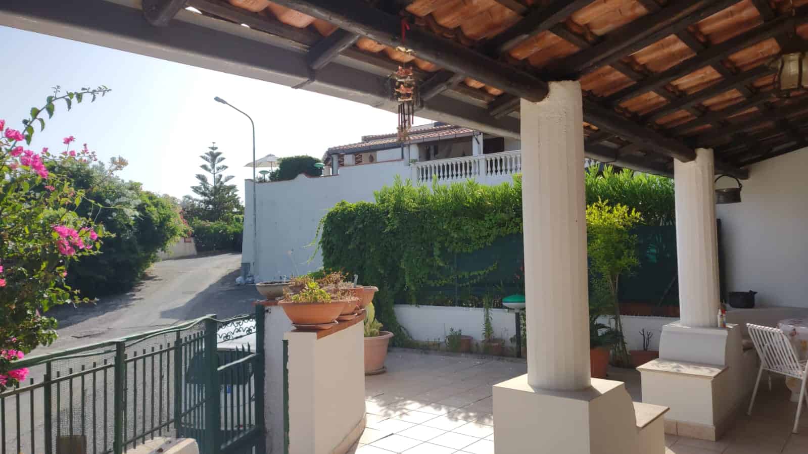 Veranda con colonne e vista sulla strada e il giardino, ideale per relax e convivialità in zona residenziale a Falcone, Me.