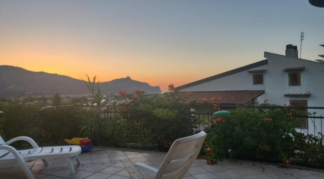 Terrazza con sedie e piante, vista sul tramonto e le colline di Falcone, Me.
