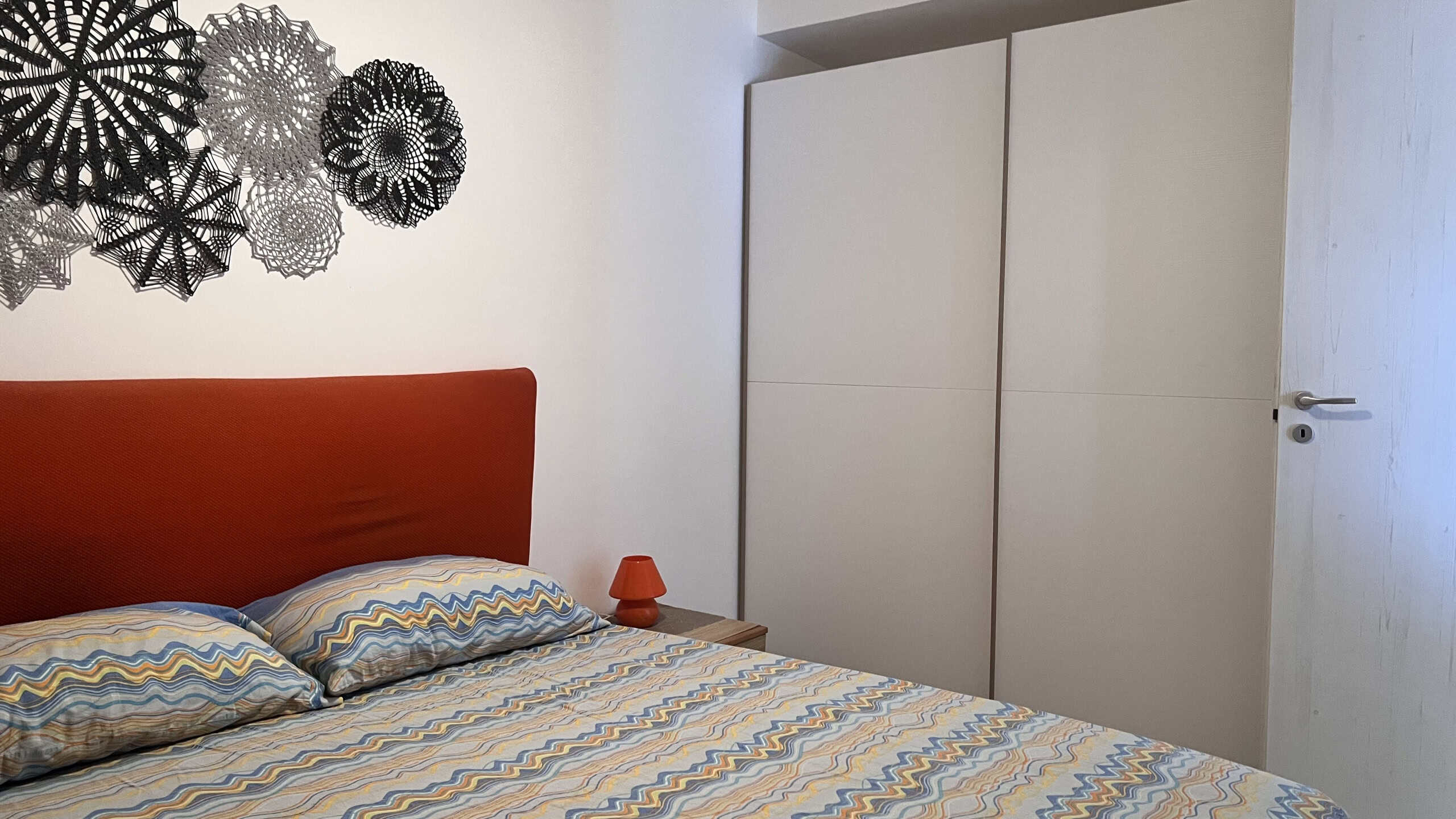Interno di una camera da letto moderna con letto matrimoniale, armadio bianco e decorazioni eleganti, ideale per appartamento in vendita a Acqualadroni.