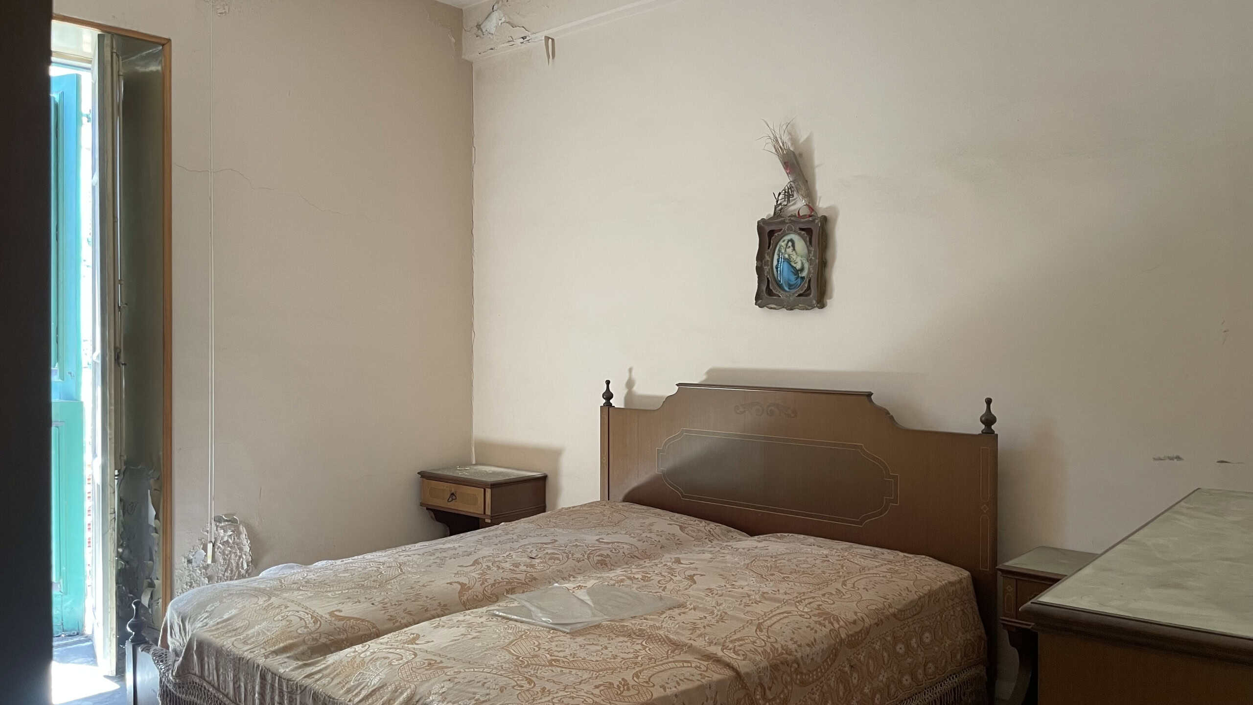 Camera da letto spaziosa con letto matrimoniale, comodini e decorazioni semplici, in un appartamento in vendita in Via Roma 168, Scaletta Zanclea, Messina.