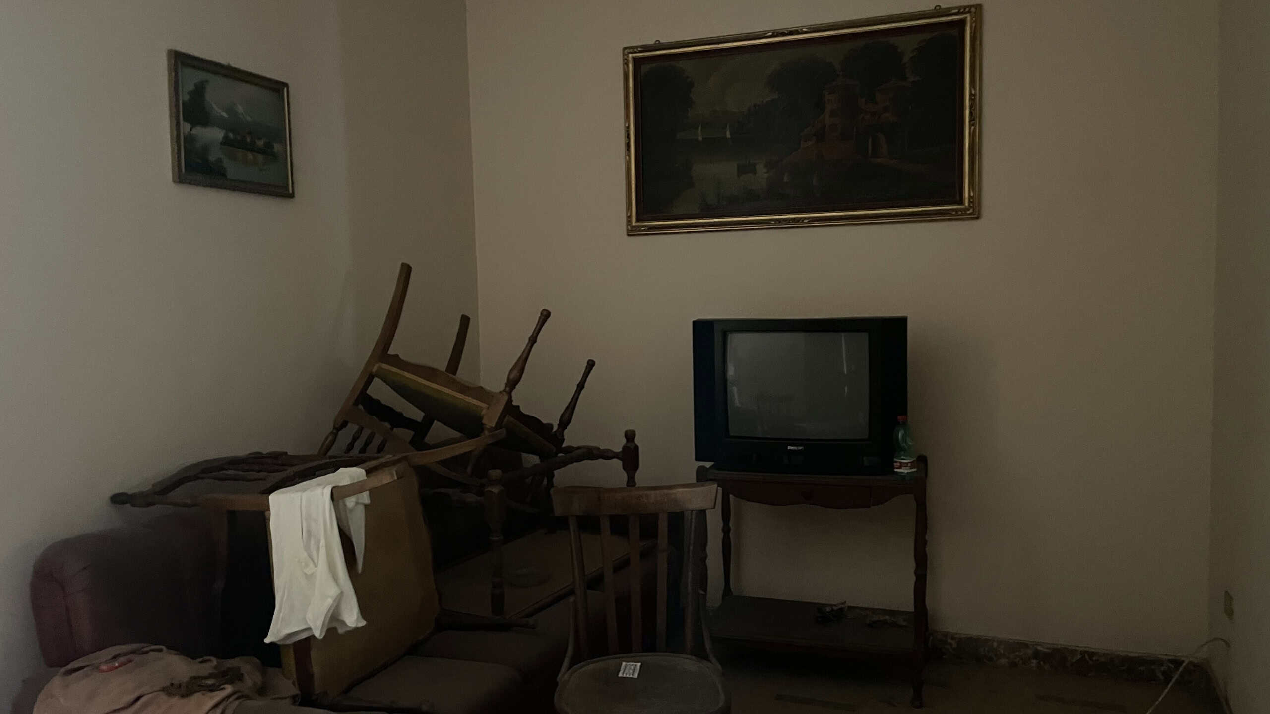 Interno di un appartamento con mobili impilati e TV, ambiente semplice e non arredato, in vendita a Scaletta Zanclea, Me.