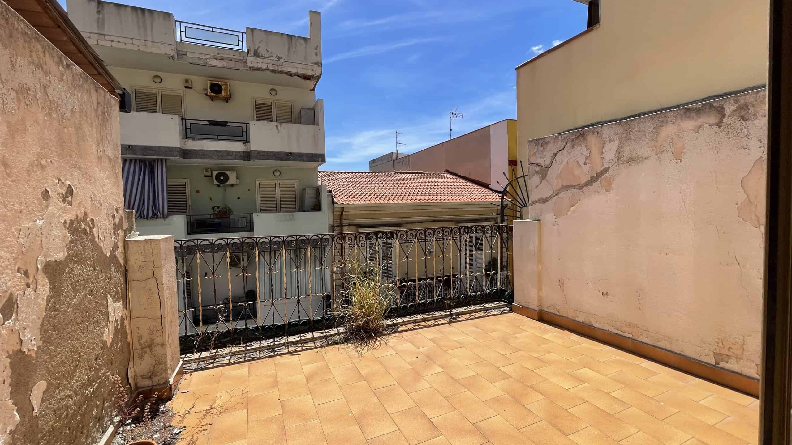 Balcone spazioso con vista su edifici circostanti e cielo azzurro, pavimentato con piastrelle in ceramica, in Scaletta Zanclea, Me.