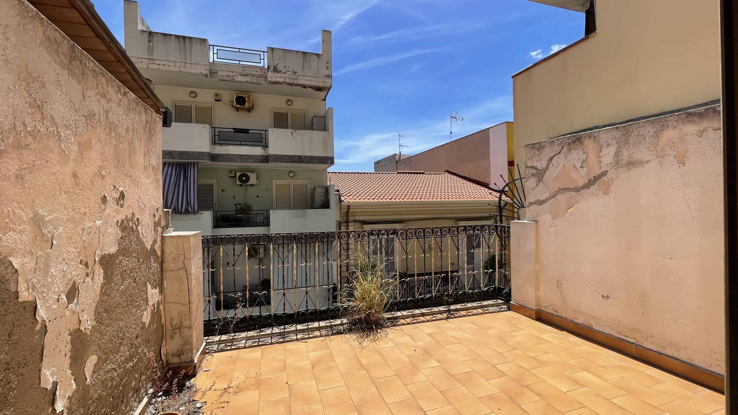 Balcone con vista sulla città di Scaletta Zanclea, con pavimentazione in piastrelle e ringhiera in ferro, in un appartamento in vendita.