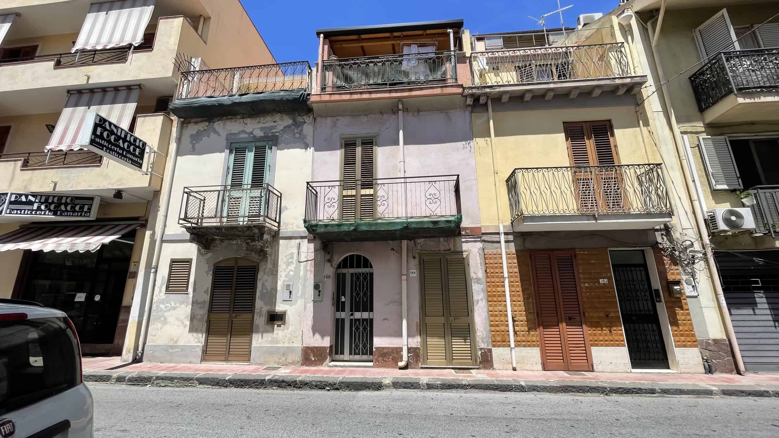 Edificio residenziale in Via Roma 168 a Scaletta Zanclea, con balconi e facciata in pietra e intonaco.