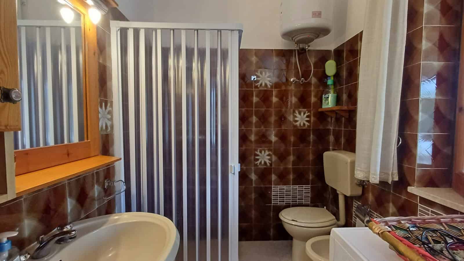 Bagno in affitto con doccia, WC e lavandino, arredato in stile semplice e funzionale.