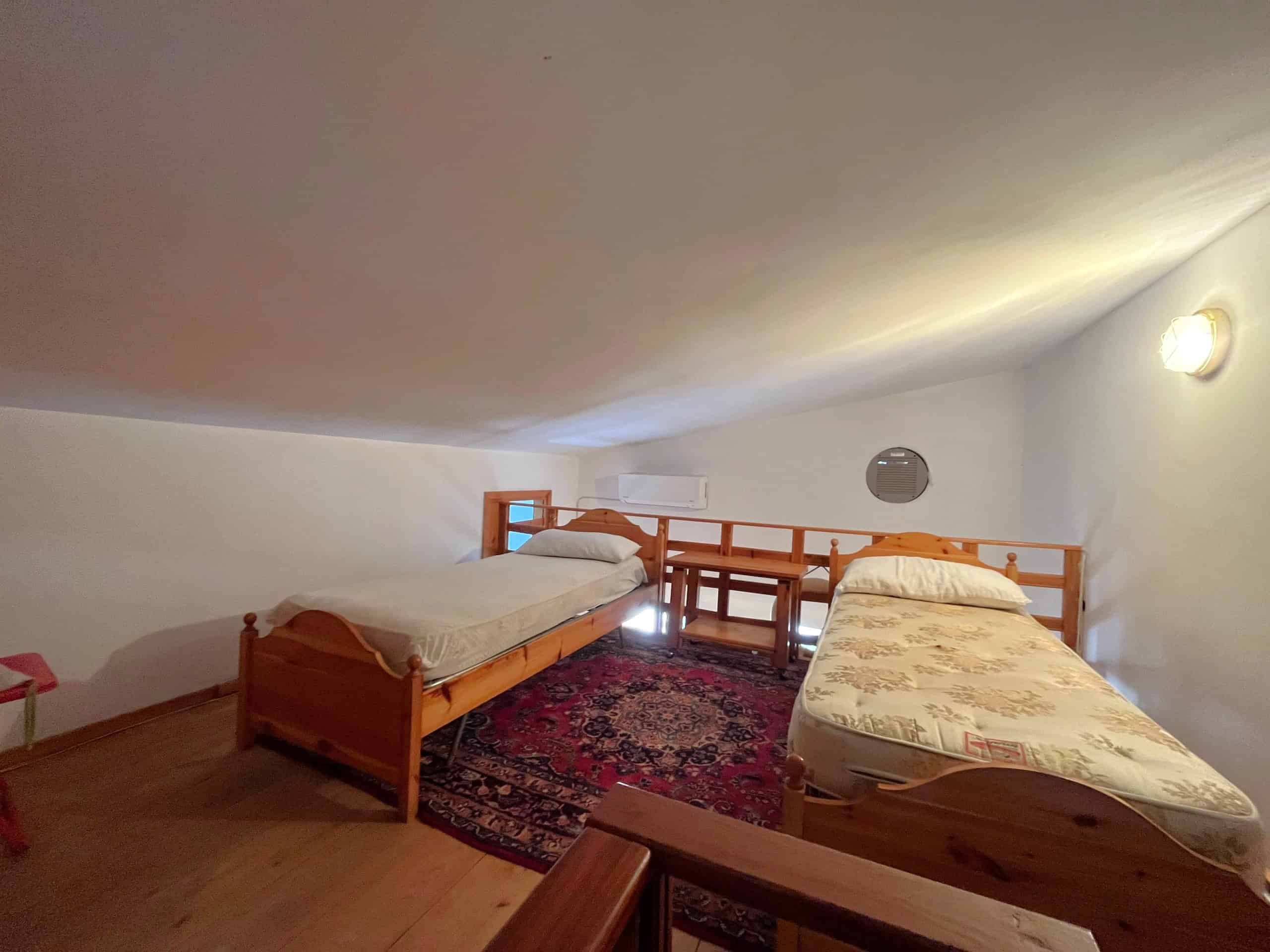 Camera da letto in una villetta in affitto a Falcone, con due letti singoli e arredamento semplice.