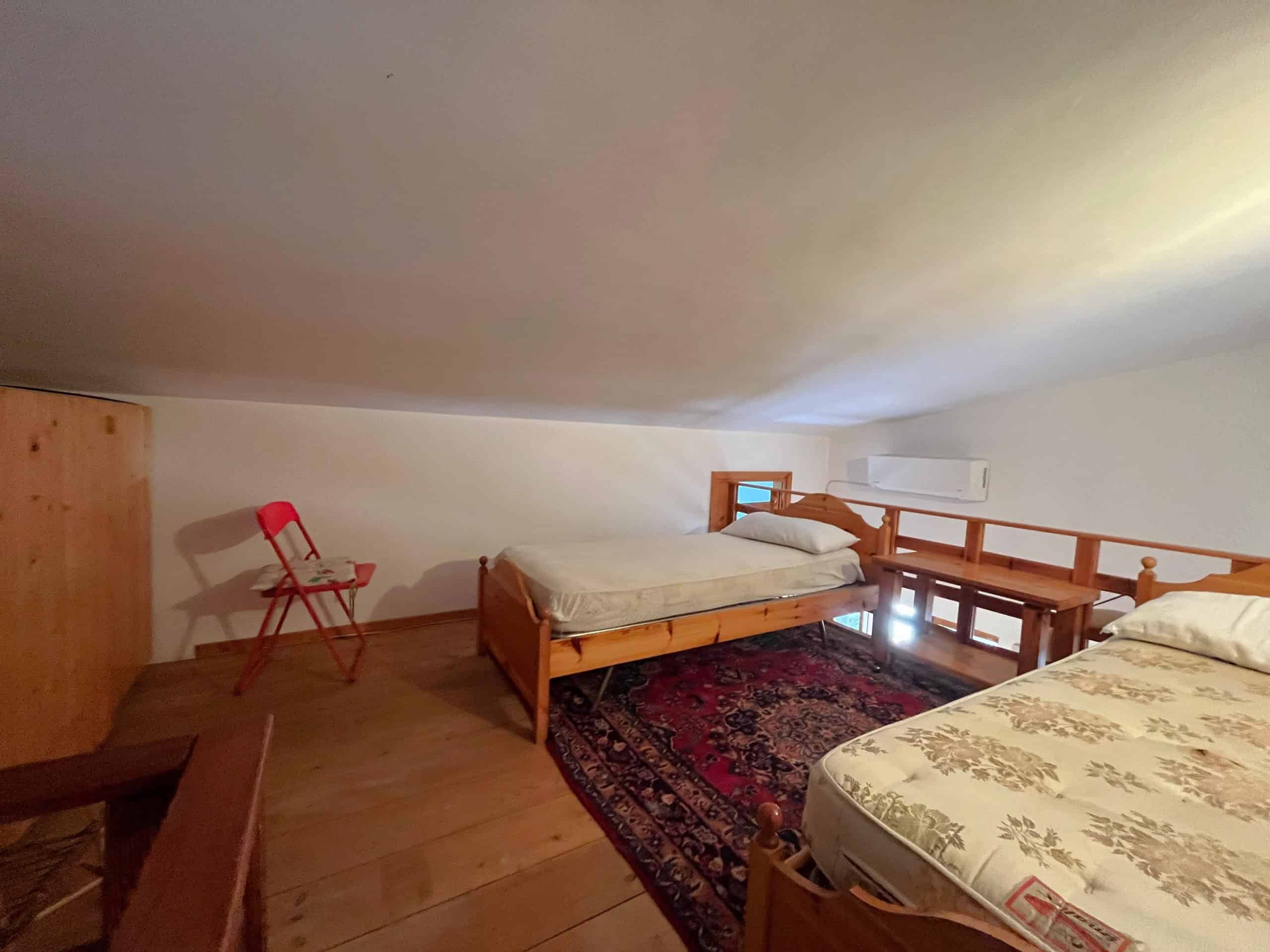 Camera mostra una camera da letto con due letti singoli, un tappeto e mobili in legno, in un ambiente luminoso e accogliente.