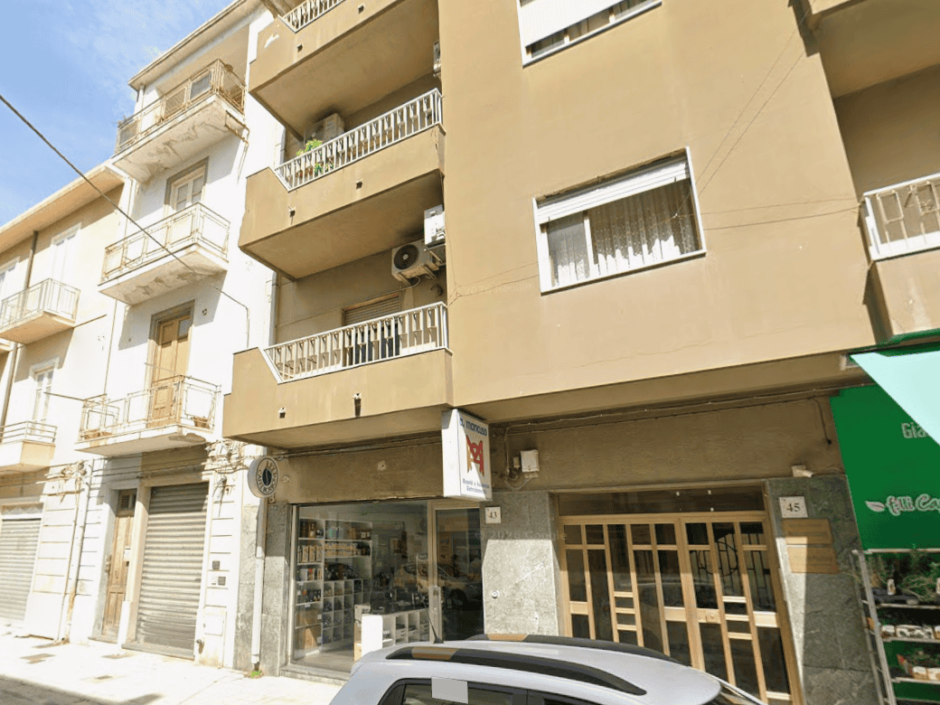Ampio negozio al piano terra di un edificio residenziale in zona urbana, con vetrina e ingresso principale, ideale per attività commerciali o uffici, situato in una strada trafficata con parcheggio ne.
