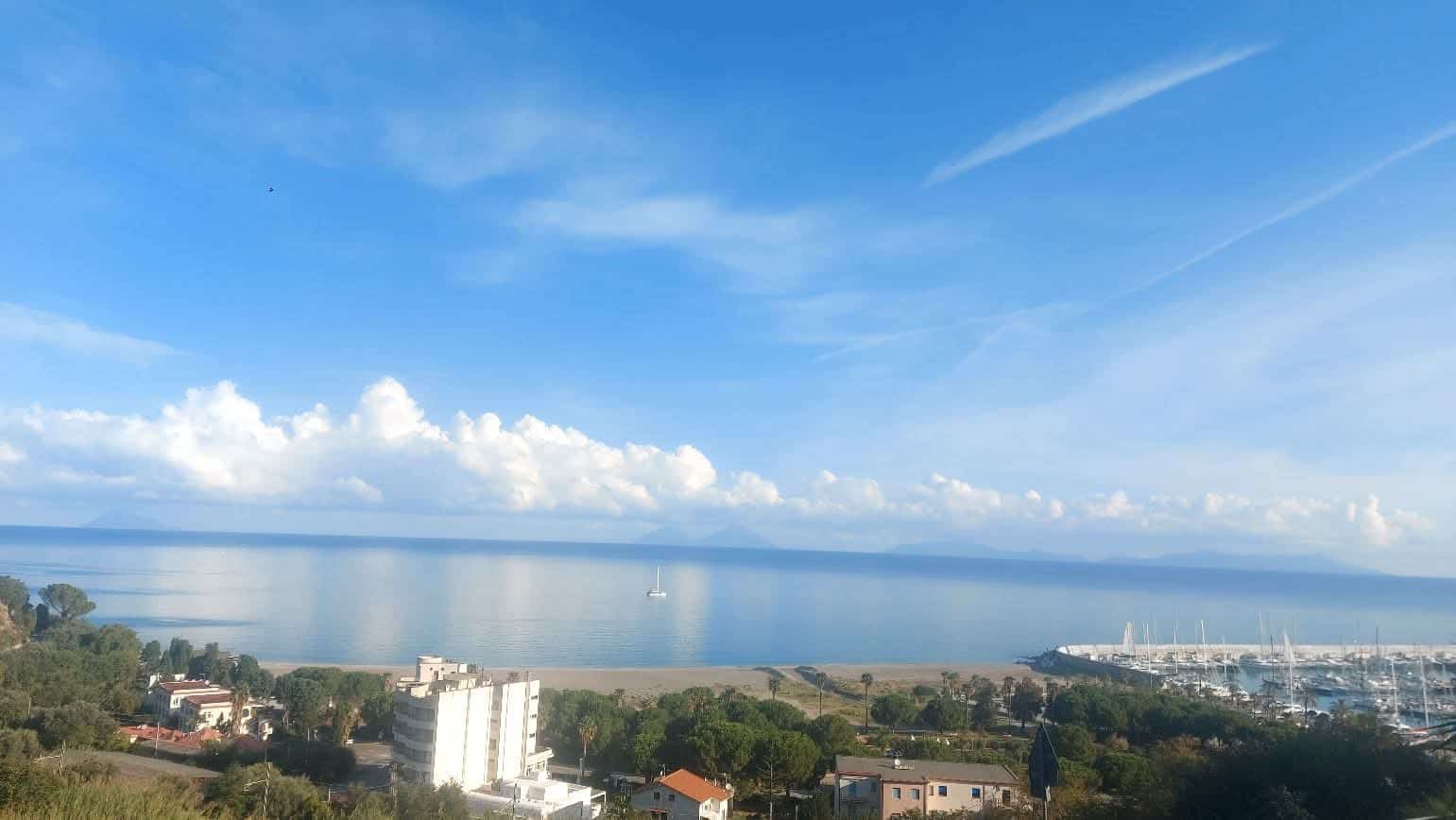 Spiaggia panoramica con vista sul mare, cielo sereno e nuvole bianche, zona residenziale vicino al lungomare, ideale per immobili e investimenti immobiliari in località costiere italiane.