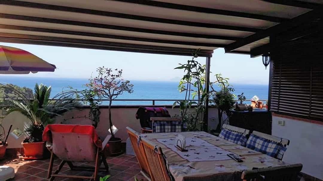Godimento di una terrazza con vista mare, arredamento elegante e piante verdi, ideale per pranzi e cene all'aperto, in un ambiente tranquillo e raffinato, perfetto per momenti di relax e convivialità.