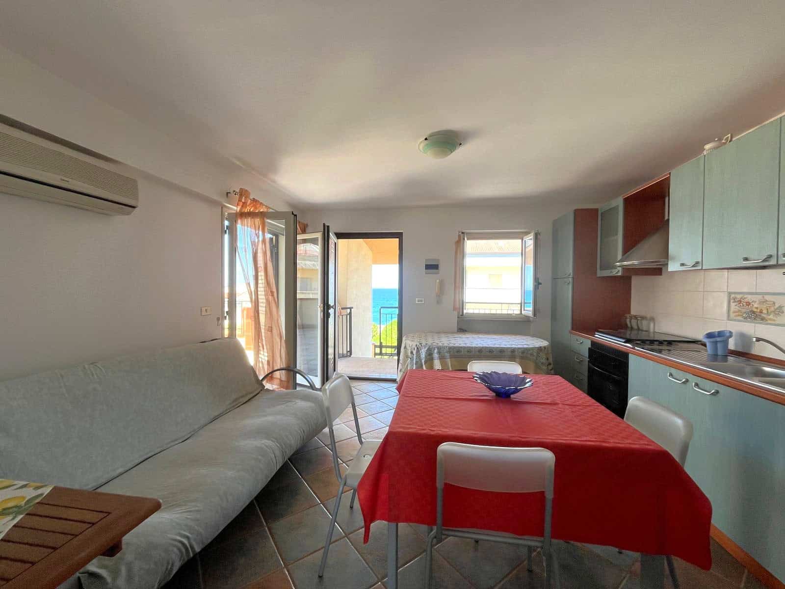 Appartamento luminoso con soggiorno, cucina e camera da letto, vista sul balcone, arredamento funzionale, ideale per vacanze o soggiorni brevi in Italia.