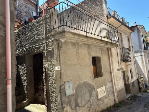 Scorcio di edificio residenziale in zona urbana con balcone e facciata in pietra, situato in un quartiere storico di città italiane. Struttura tipica con dettagli architettonici tradizionali e accesso.