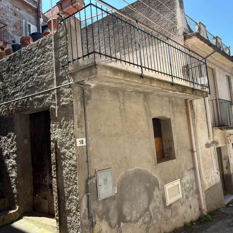 Scorcio di edificio residenziale in zona urbana con balcone e facciata in pietra, situato in un quartiere storico di città italiane. Struttura tipica con dettagli architettonici tradizionali e accesso.