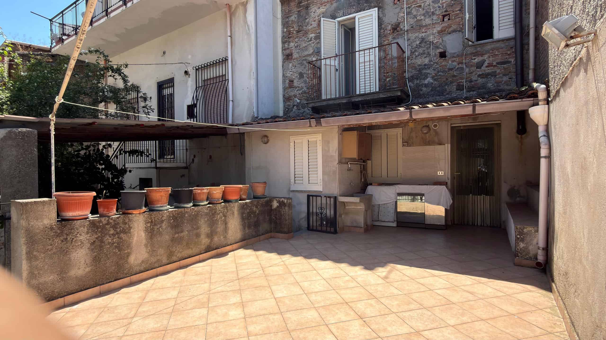 Ampio terrazzo esterno con piante in vaso e area relax, ideale per vivere all'aperto e godersi il sole in un contesto residenziale tranquillo.