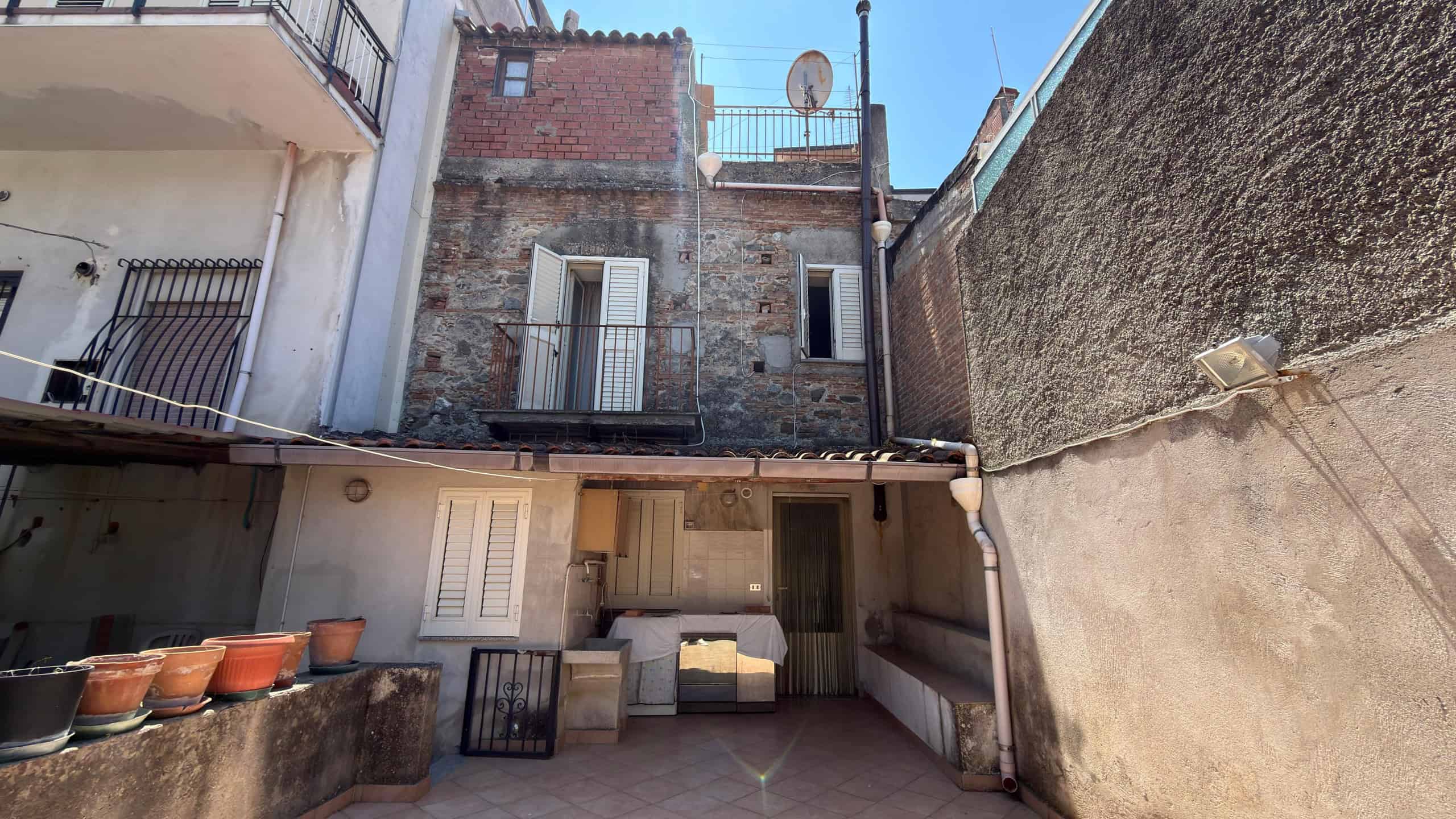 Ampio cortile interno di un edificio storico con pareti in pietra e spazi esterni per relax e socializzazione, ideale per ristrutturazioni e valorizzazione immobiliare.