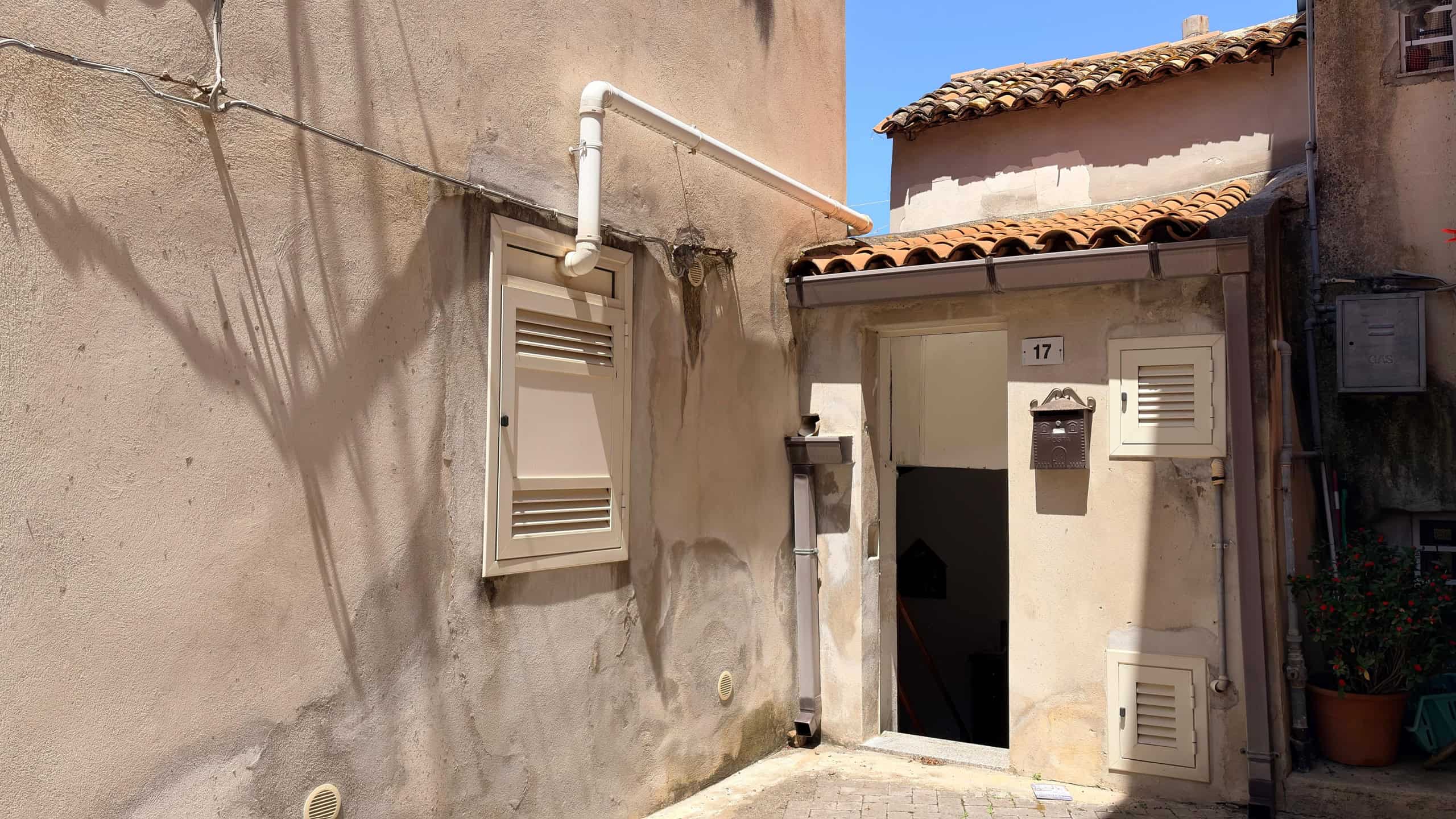 Pannelli di accesso alle utenze e parete esterna di un edificio storico in stile mediterraneo, con tubature e scatole di distribuzione, in un contesto urbano autentico e caratteristico.